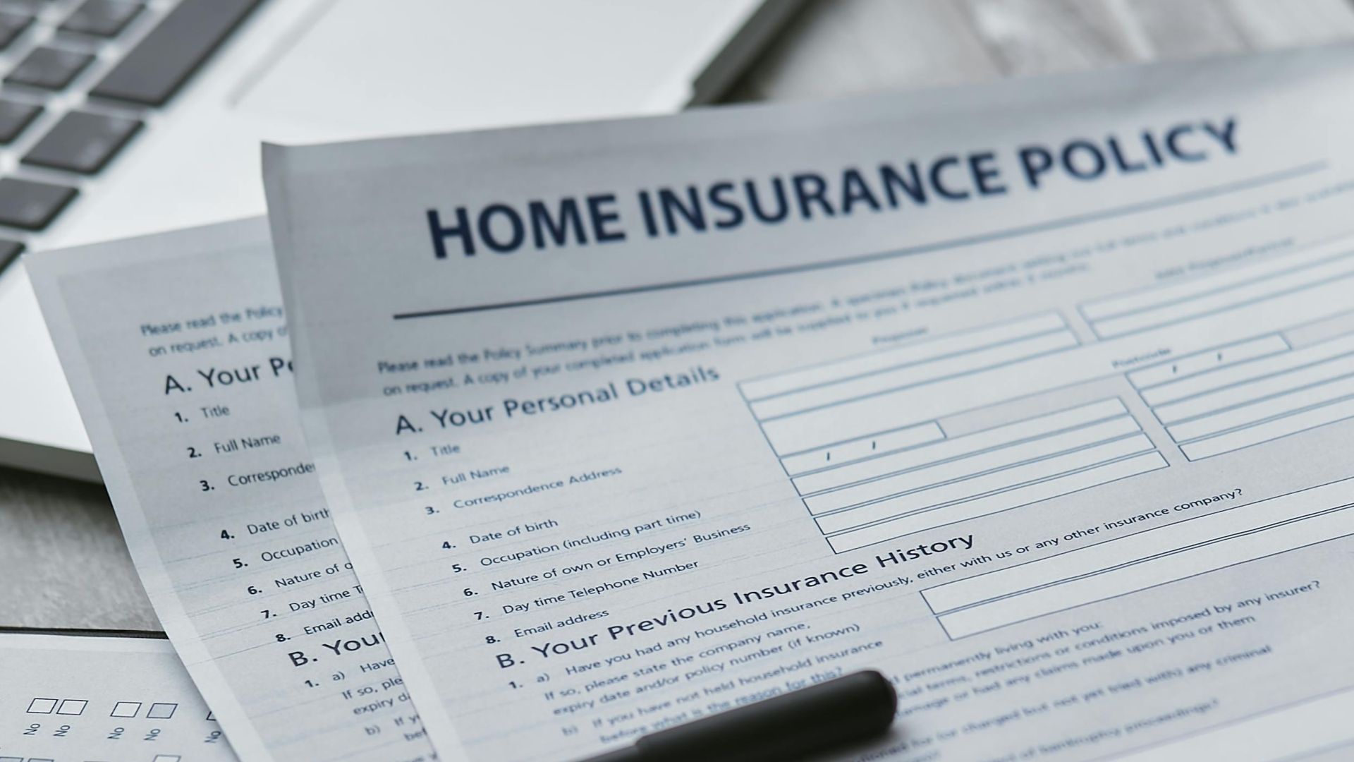 Close-up of home insurance documents with a laptop for financial planning.