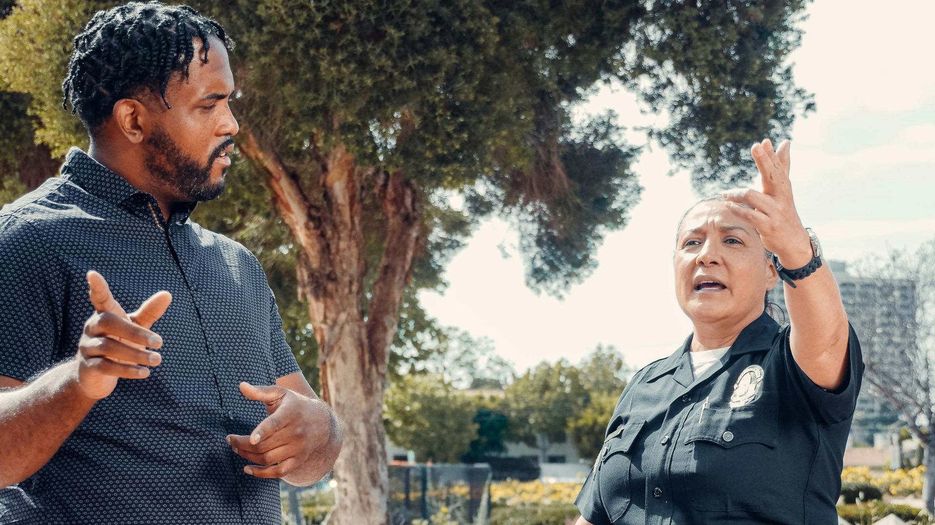 A police officer and a community member engaging in a discussion outdoors on a sunny day.