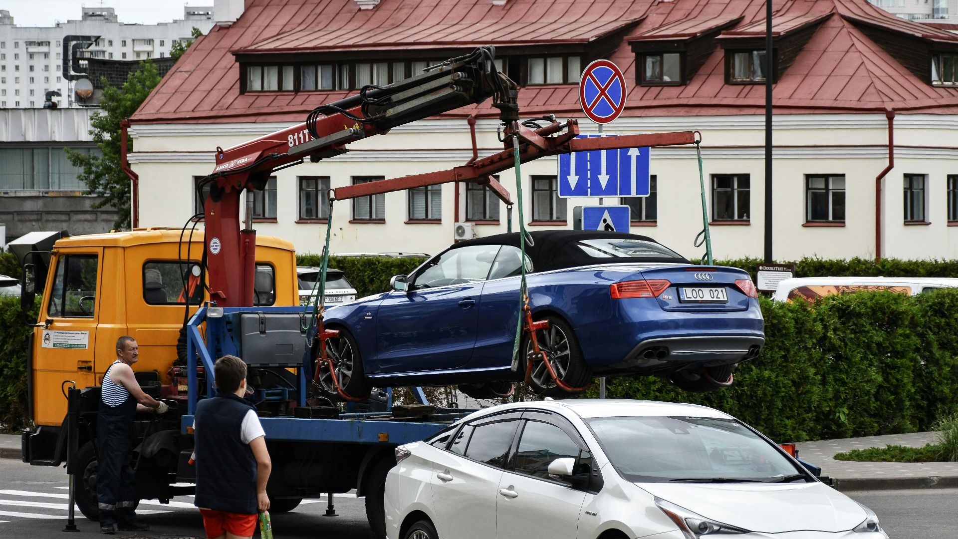 Towing a blue Audi convertible in a bustling city street.