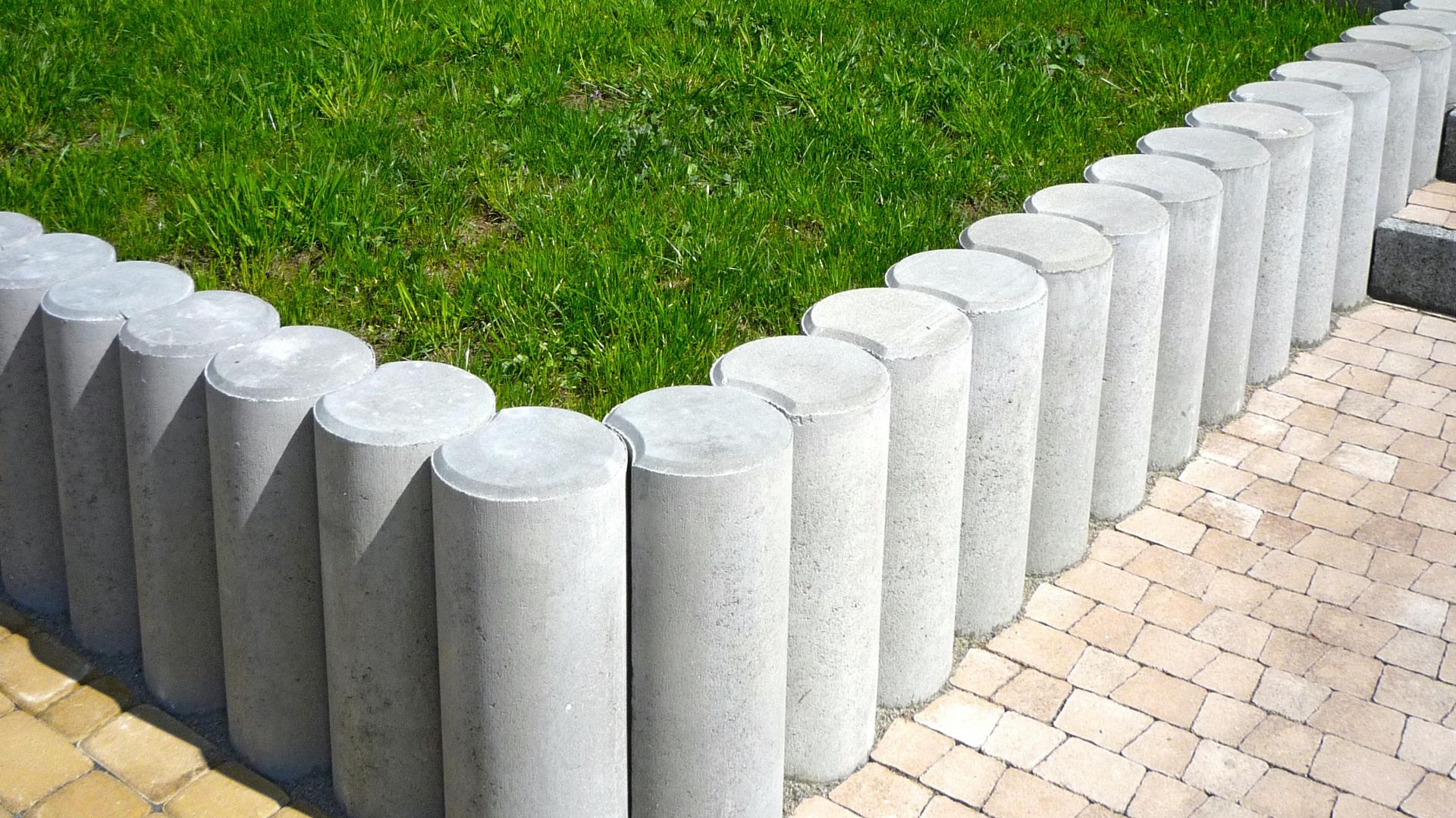 Cylindrical concrete blocks form a stylish lawn boundary, enhancing garden aesthetics.
