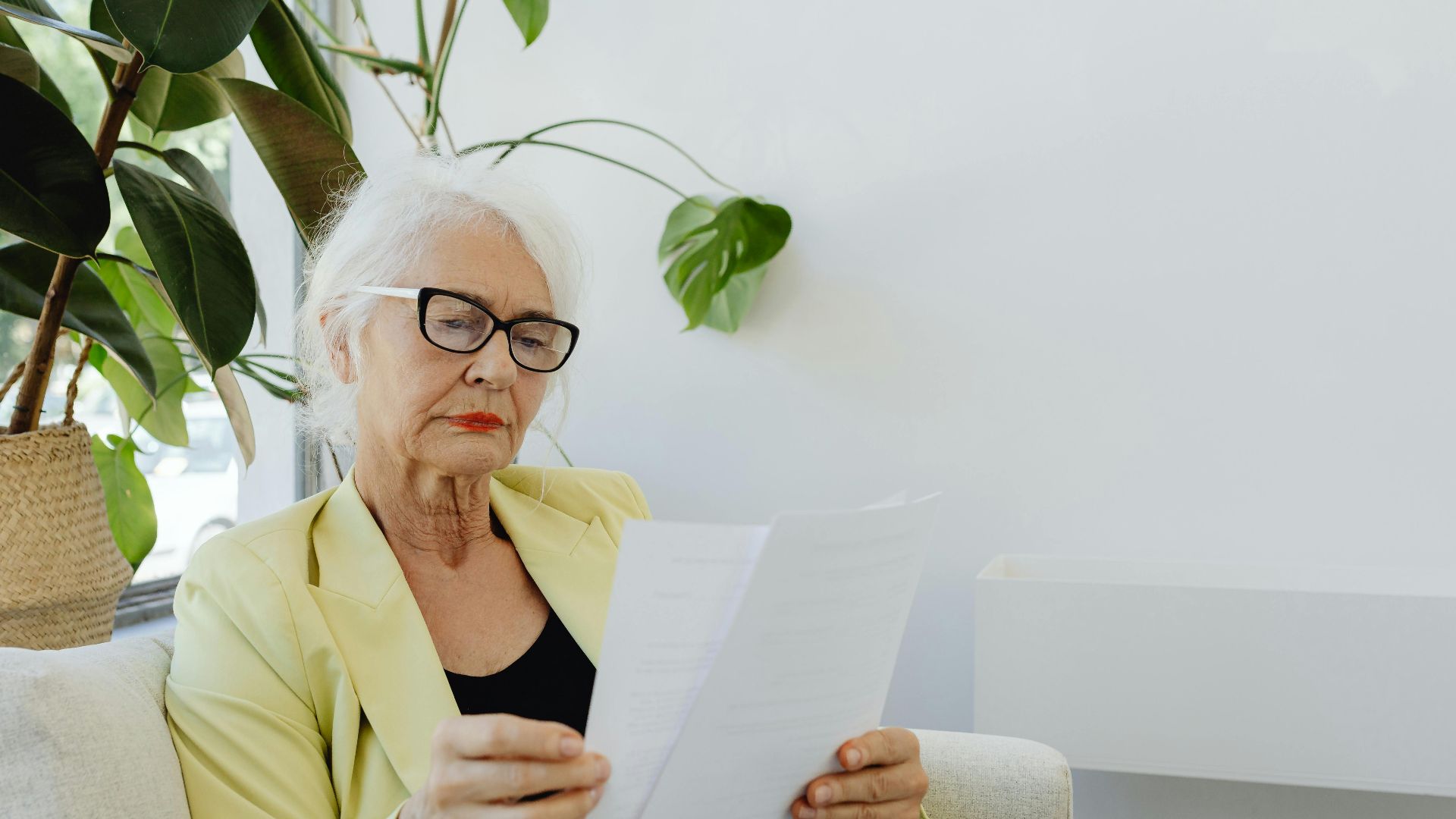 Portrait of a senior businesswoman in a blazer reading documents indoors.