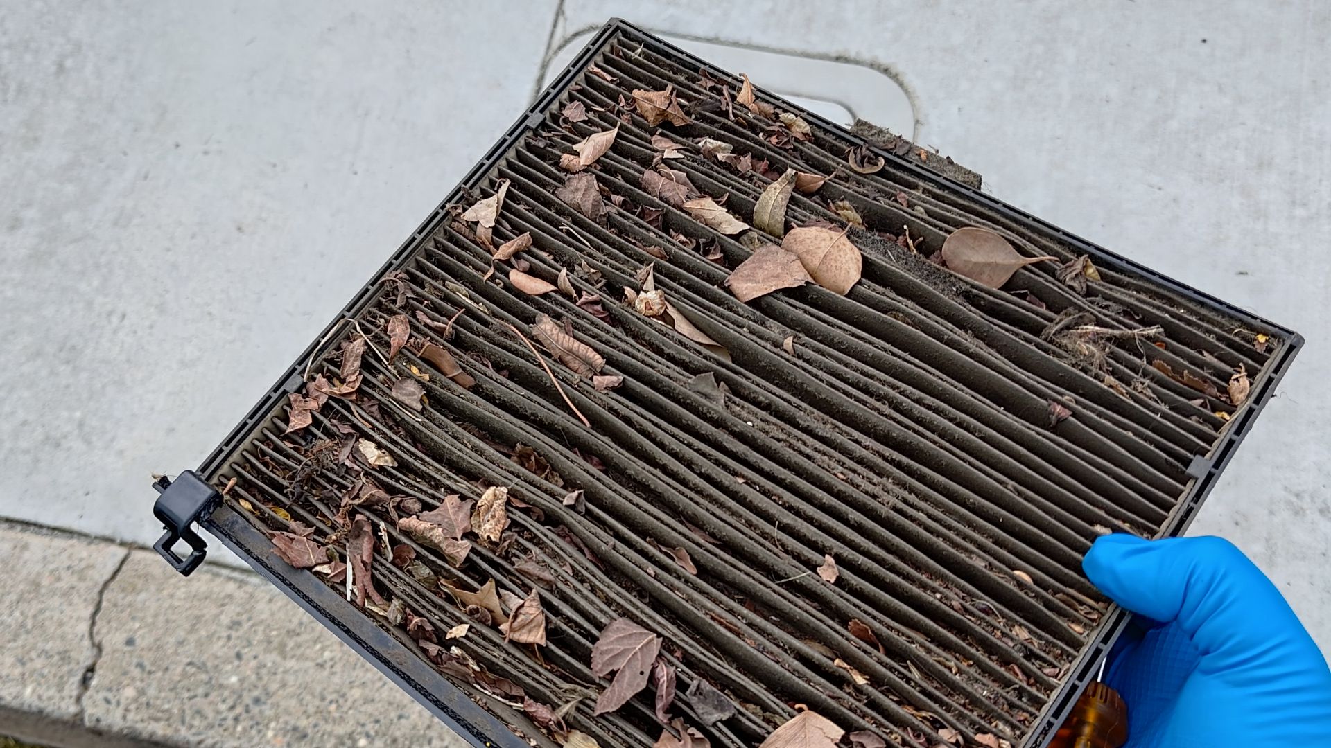 A dirty cabin filter clogged with leaves and dirt