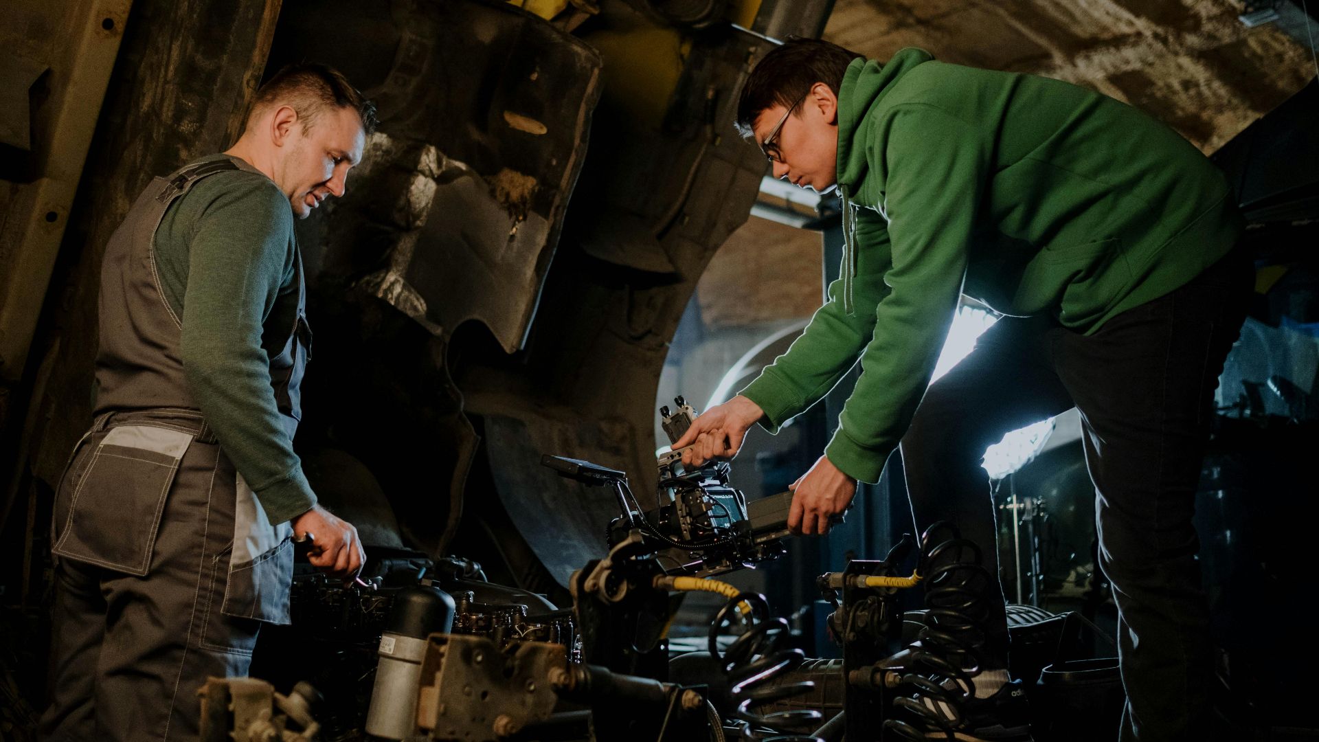 Two mechanics engaged in repairing an engine, showcasing teamwork in an industrial setting.