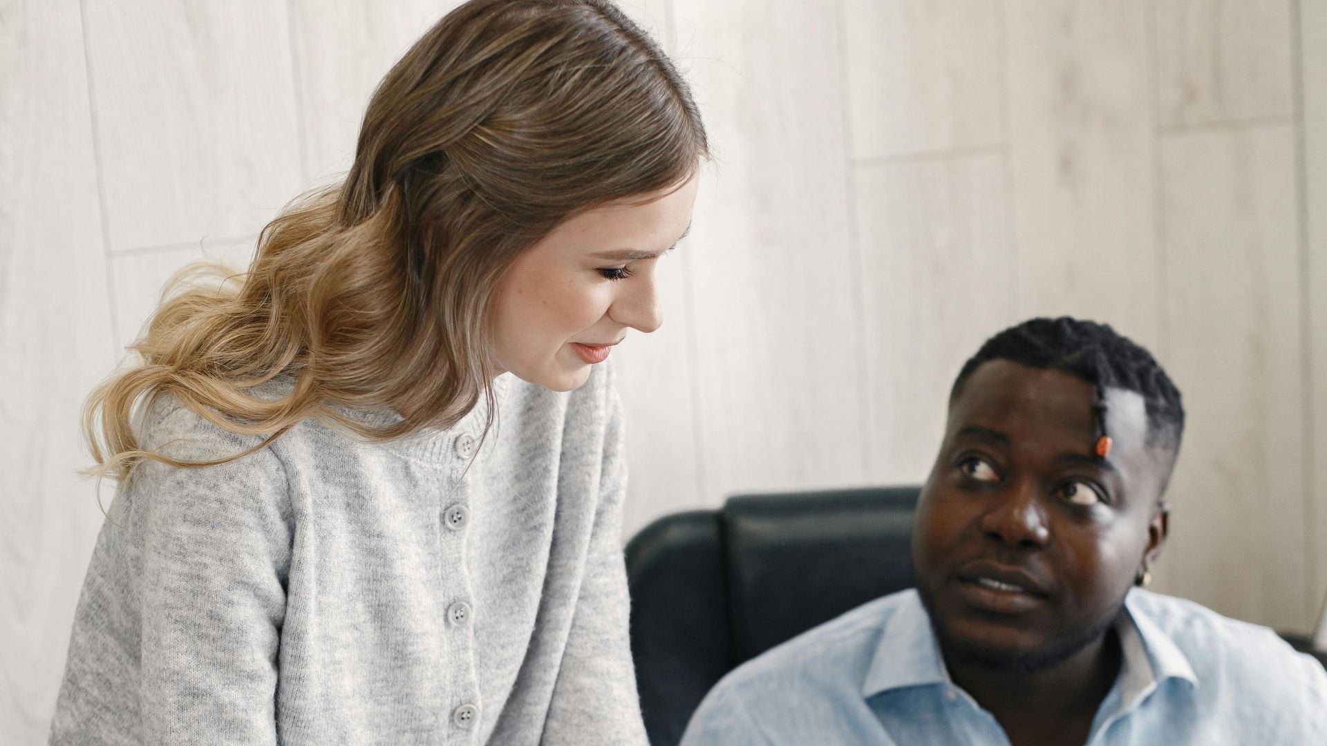 Two professionals discussing work in an office environment, promoting teamwork and diversity.