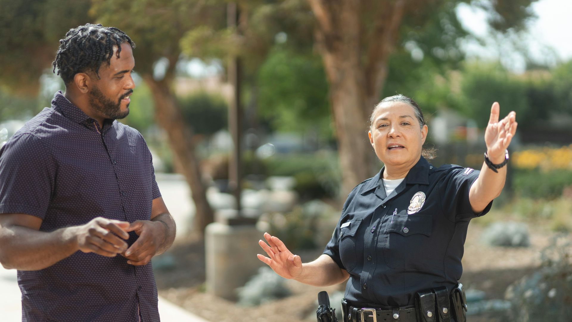Police officer in uniform engaging in a conversation with a man on a sunny day, promoting community relations.