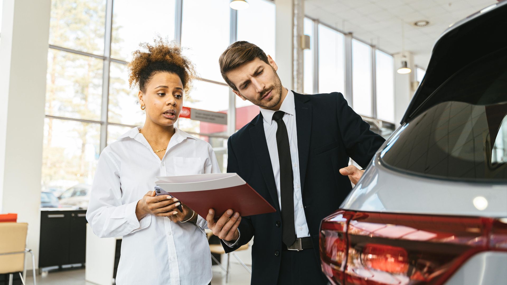 A professional consultation at a car dealership involving a sales agent and a customer discussing a vehicle purchase.
