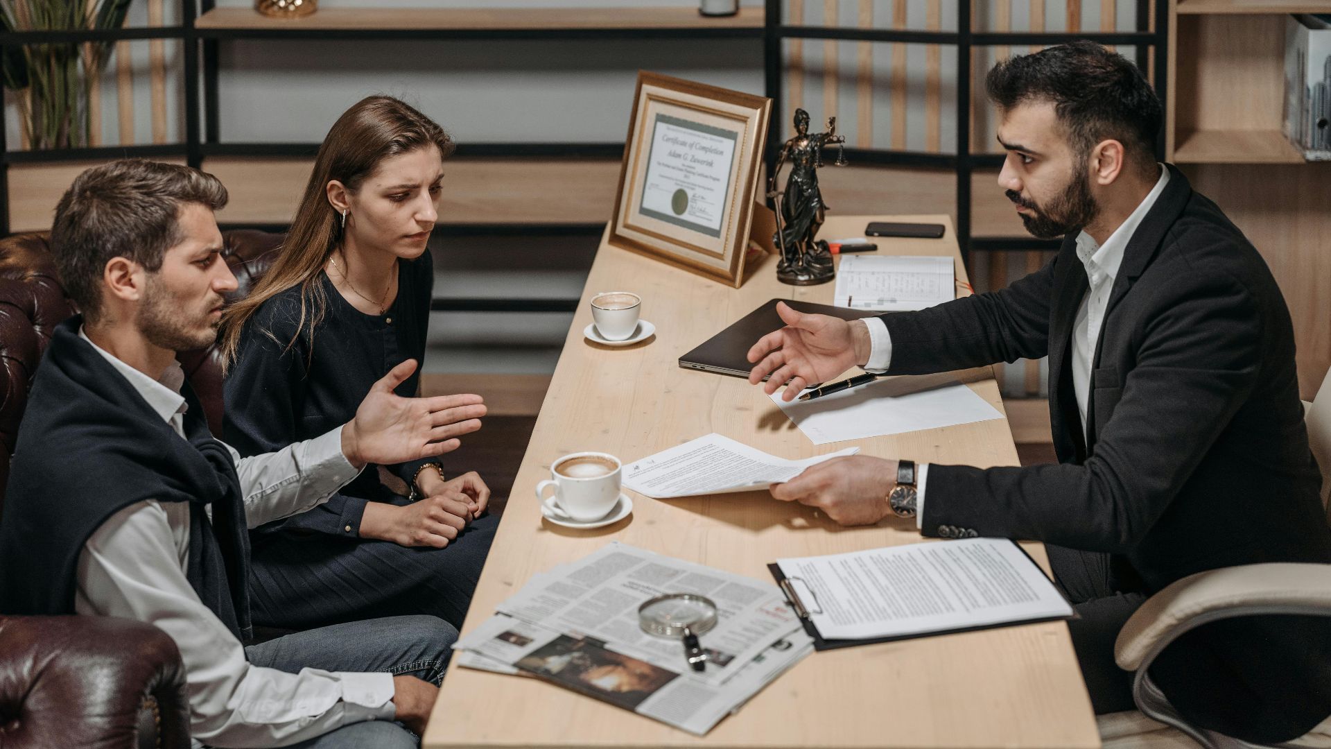 Lawyer consulting clients in an office. Documents and coffee on the table.