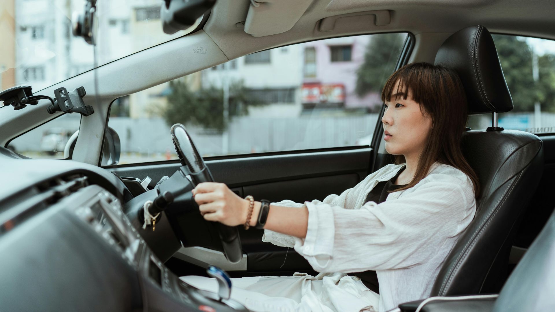 Confident young woman driving in the city, focused and pensive.