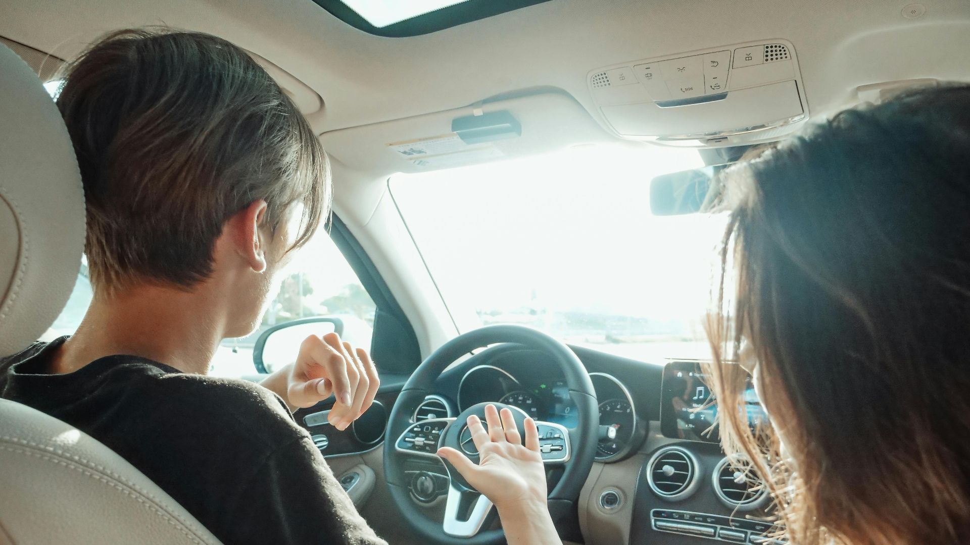 A view of two adults talking inside a car during the day, highlighting interpersonal communication.