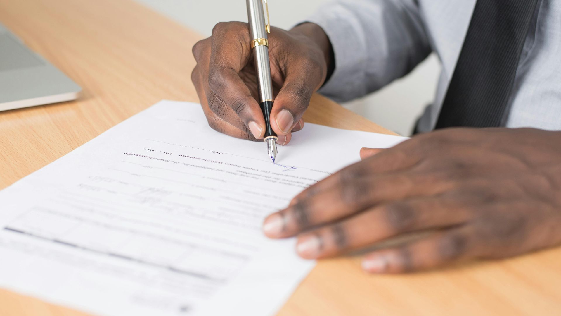 Close-up of a businessman signing a contract at an office desk.
