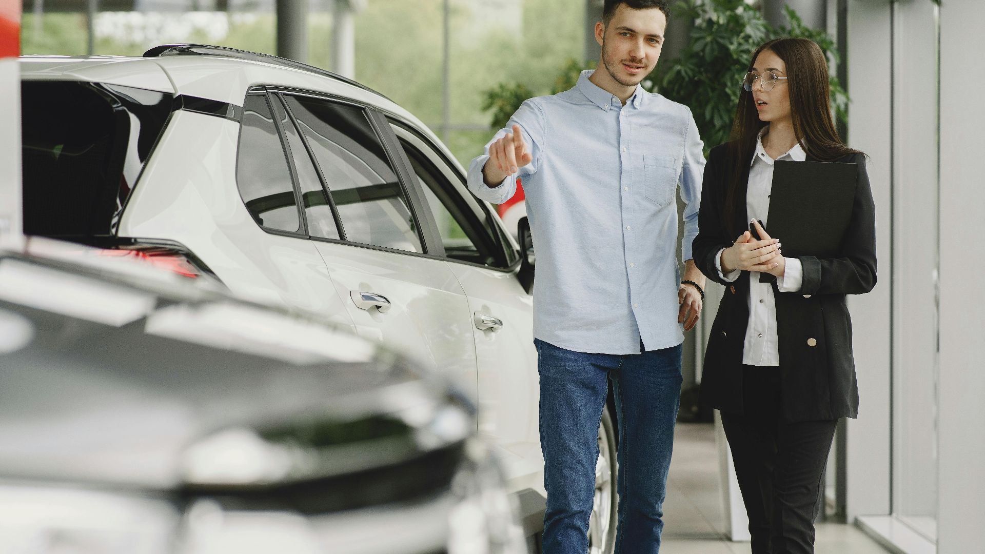 Customer and salesperson discussing a vehicle inside a modern car dealership showroom.