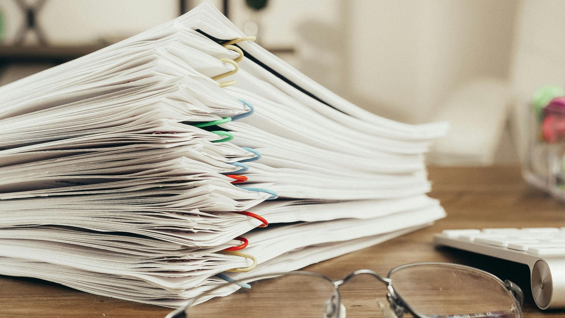 Close-up of a stack of office papers on a desk with glasses, emphasizing organization.