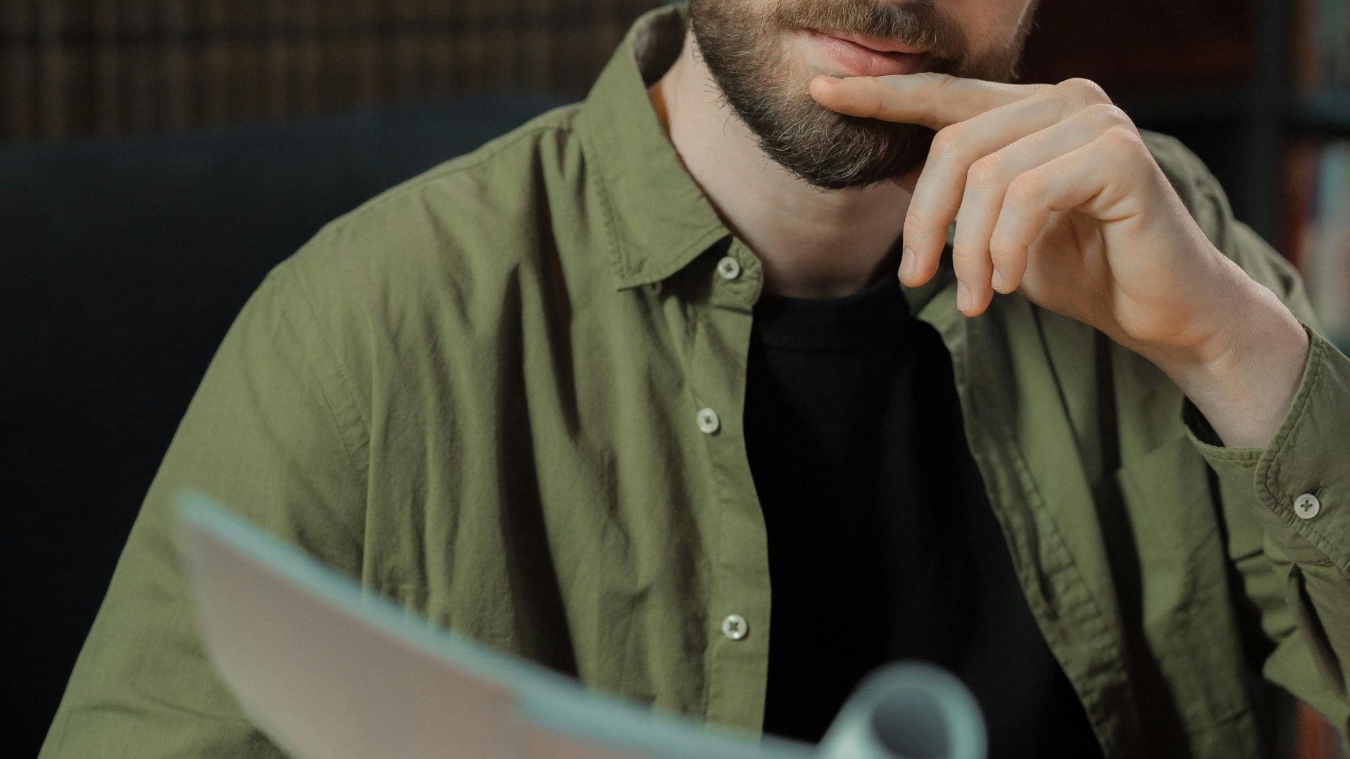 A focused writer in a library reviewing documents, deep in thought.