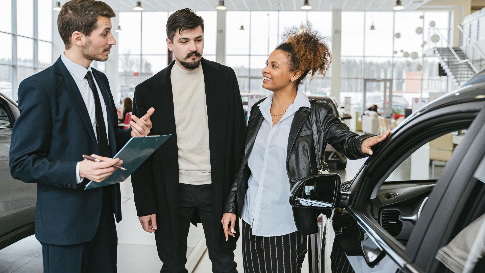 A diverse team of adults discussing a car purchase in a dealership showroom.