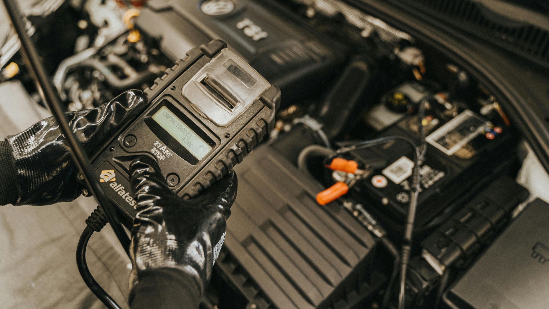 Mechanic diagnosing a car engine with a diagnostic tool, showcasing technical expertise and automotive care.