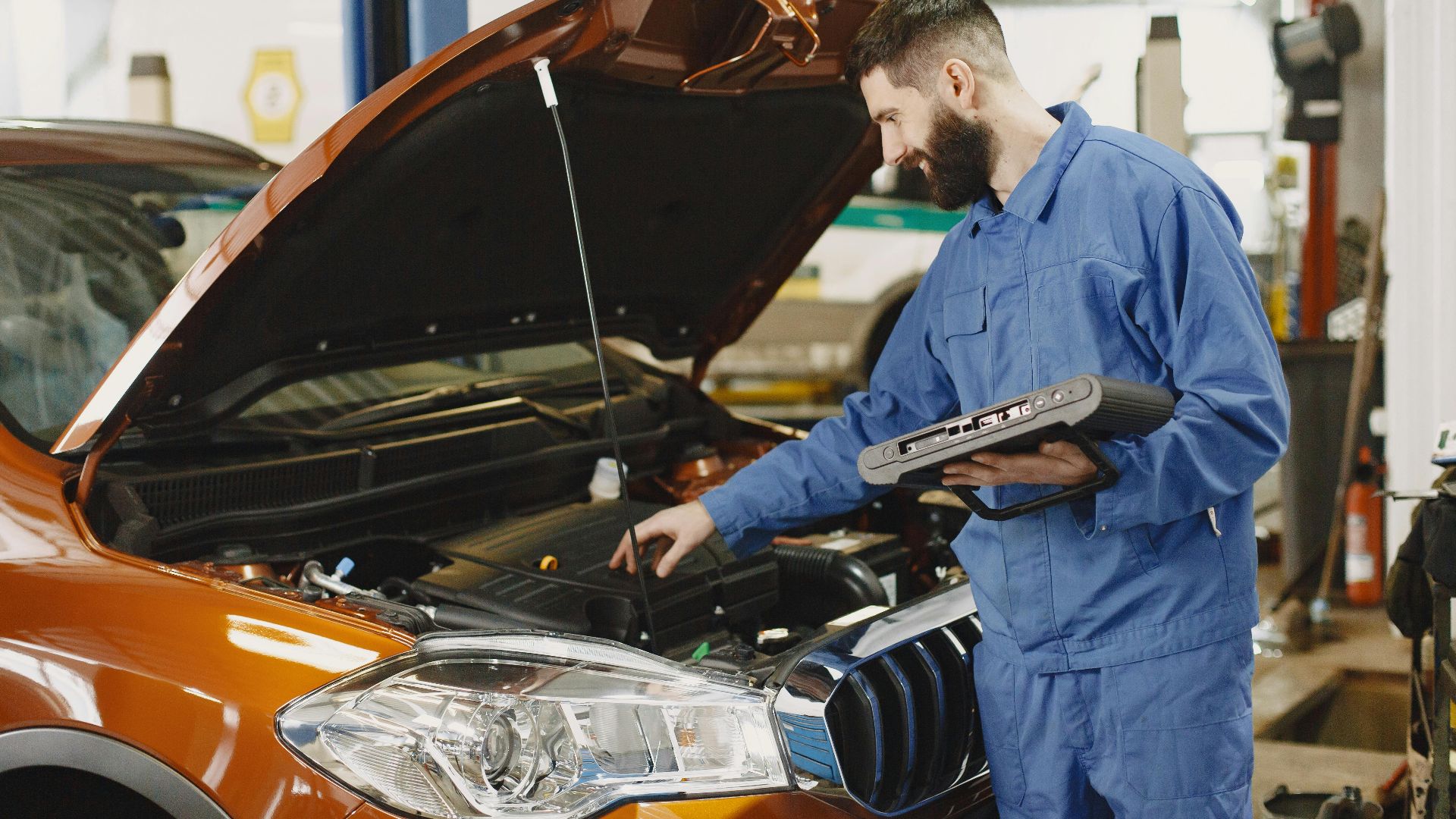 Skilled mechanic working on car engine diagnostics in a modern garage.