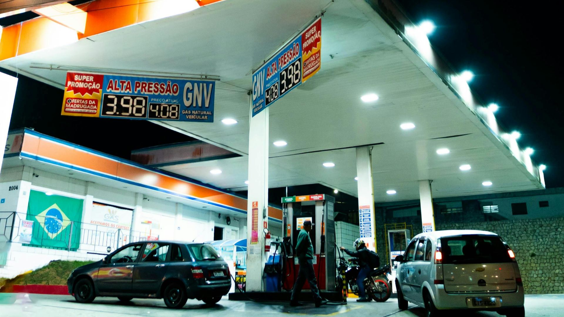Night view of a well-lit gas station with multiple cars fueling, highlighting the station's modern architecture.