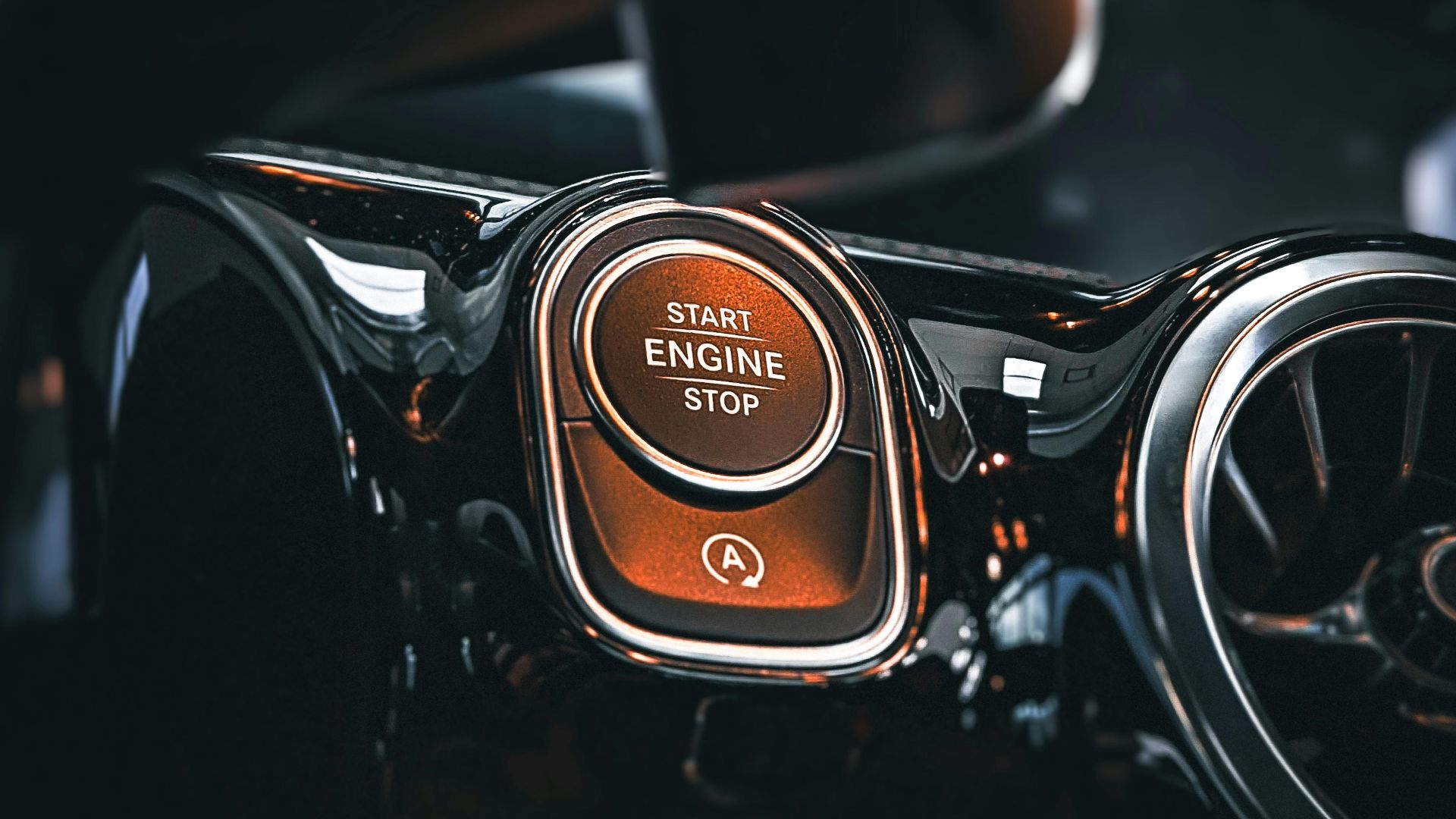 Close-up of a luxury car's start engine stop button on a sleek dashboard.