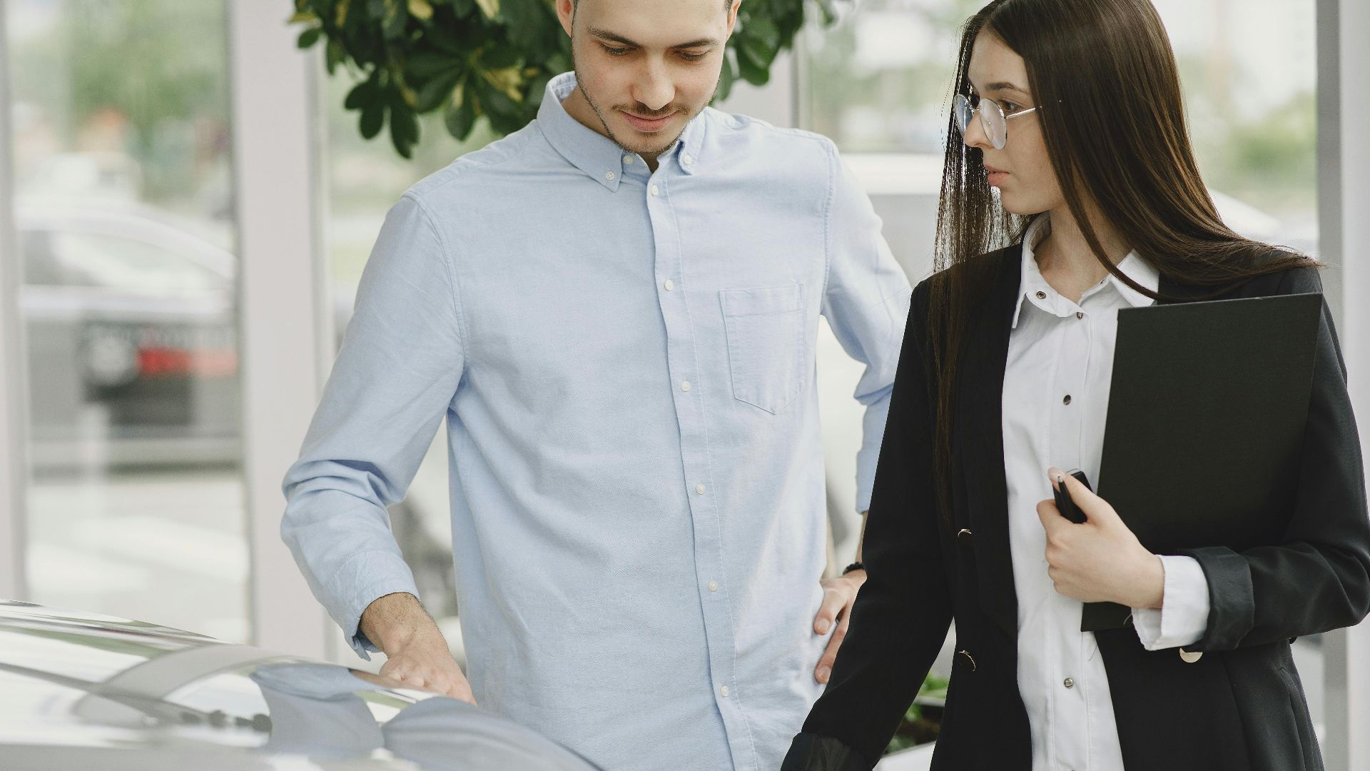 Professional interaction between a client and salesperson in a car dealership setting.
