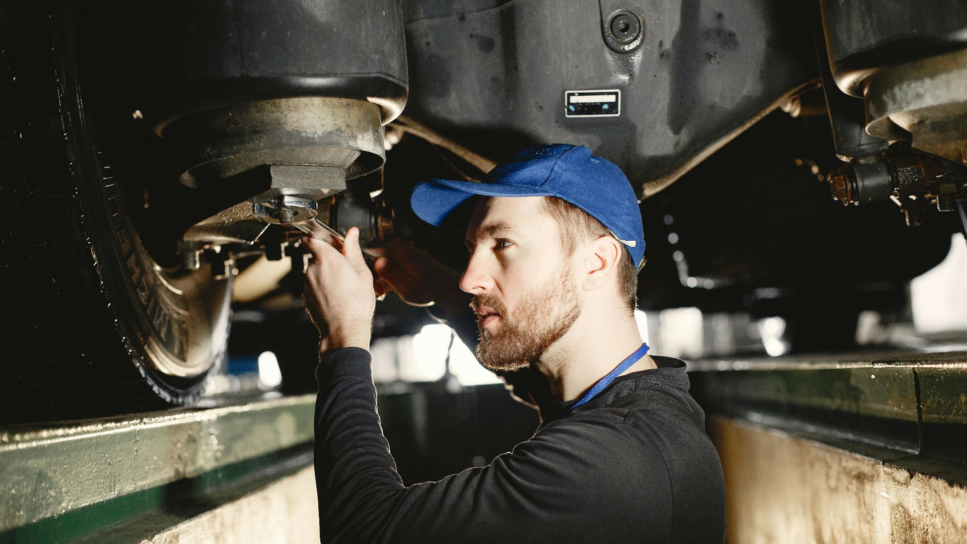 Auto mechanic working diligently on vehicle in workshop setting. Expertise in repair and maintenance.