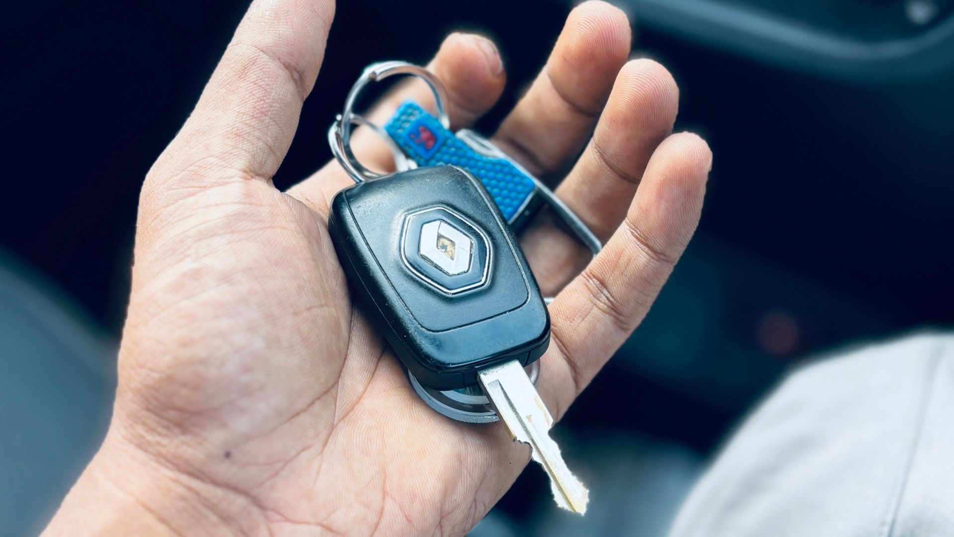 Hand holding car keys inside a vehicle, showing dashboard details.