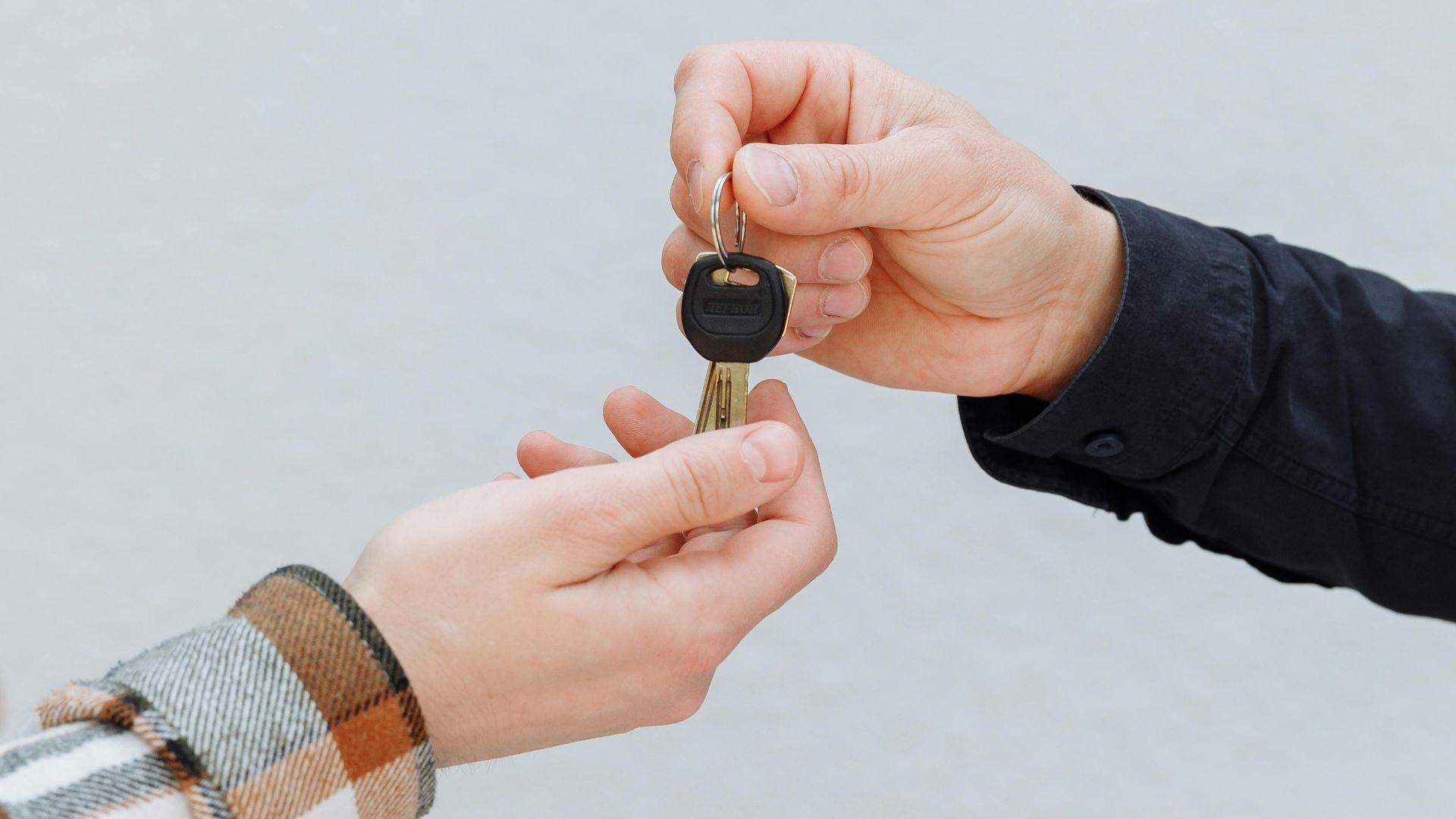 Close-up of hands exchanging car keys, symbolizing a business transaction.