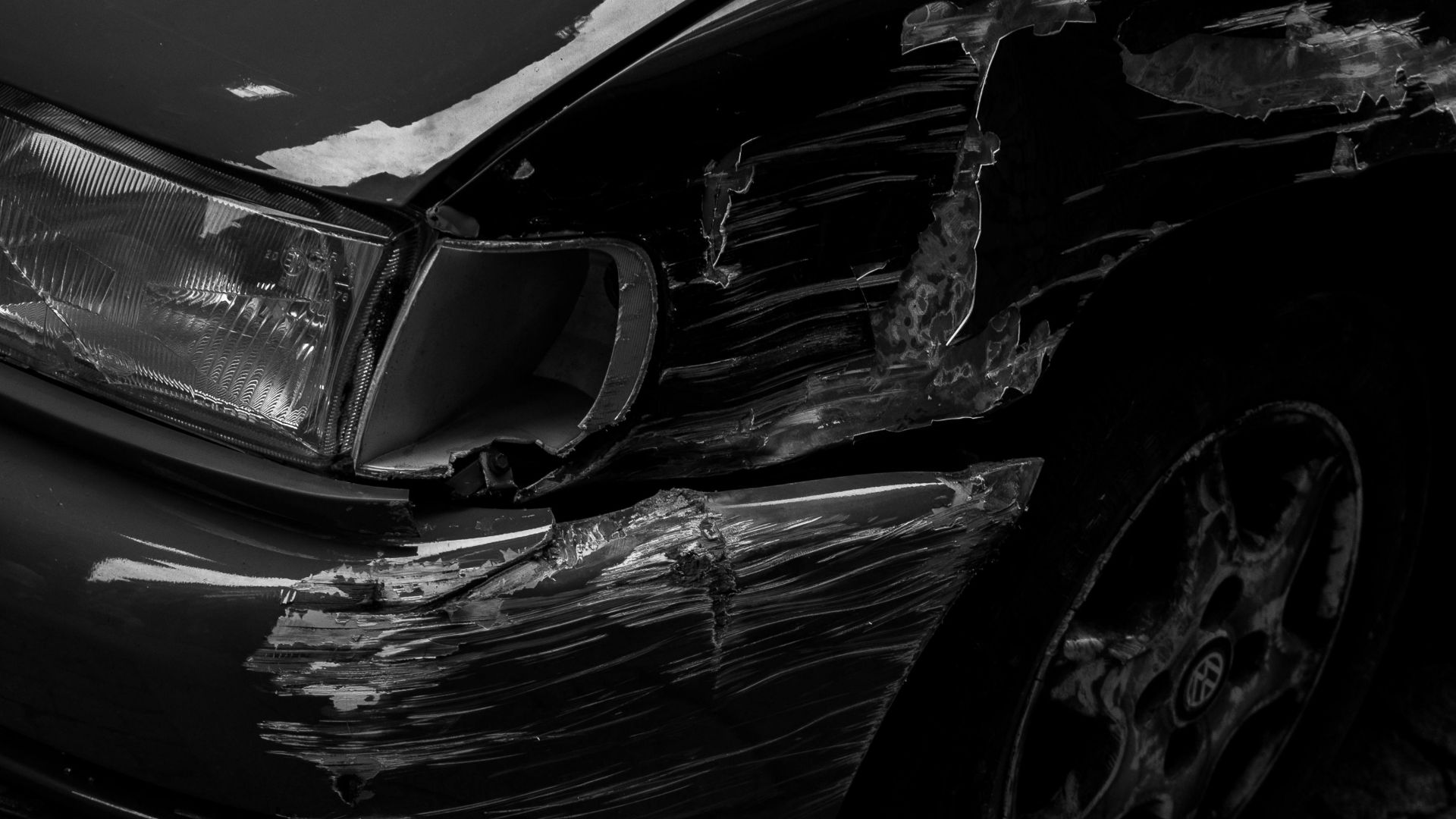 Artistic black and white image of a scratched car fender parked on a cobblestone sidewalk in Porto.