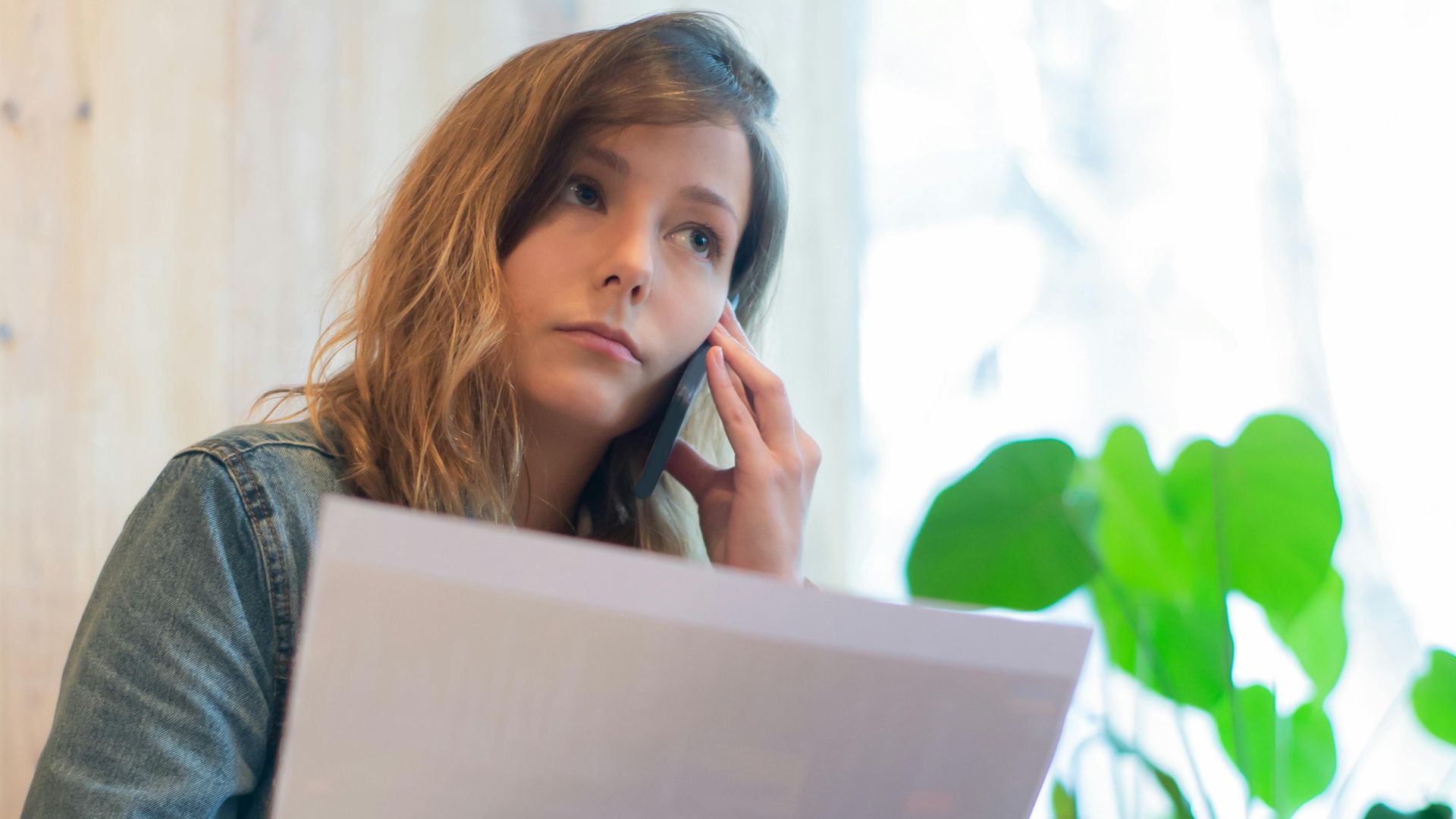 Focused businesswoman reviewing documents in a bright office with natural light.
