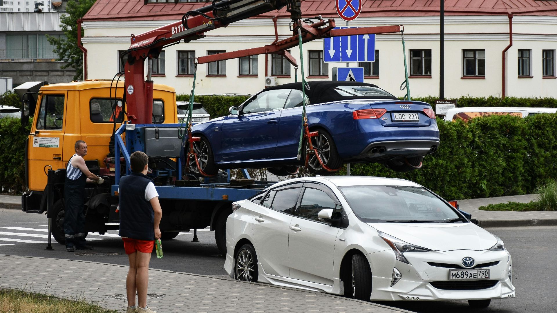 Towing a blue Audi convertible in a bustling city street.