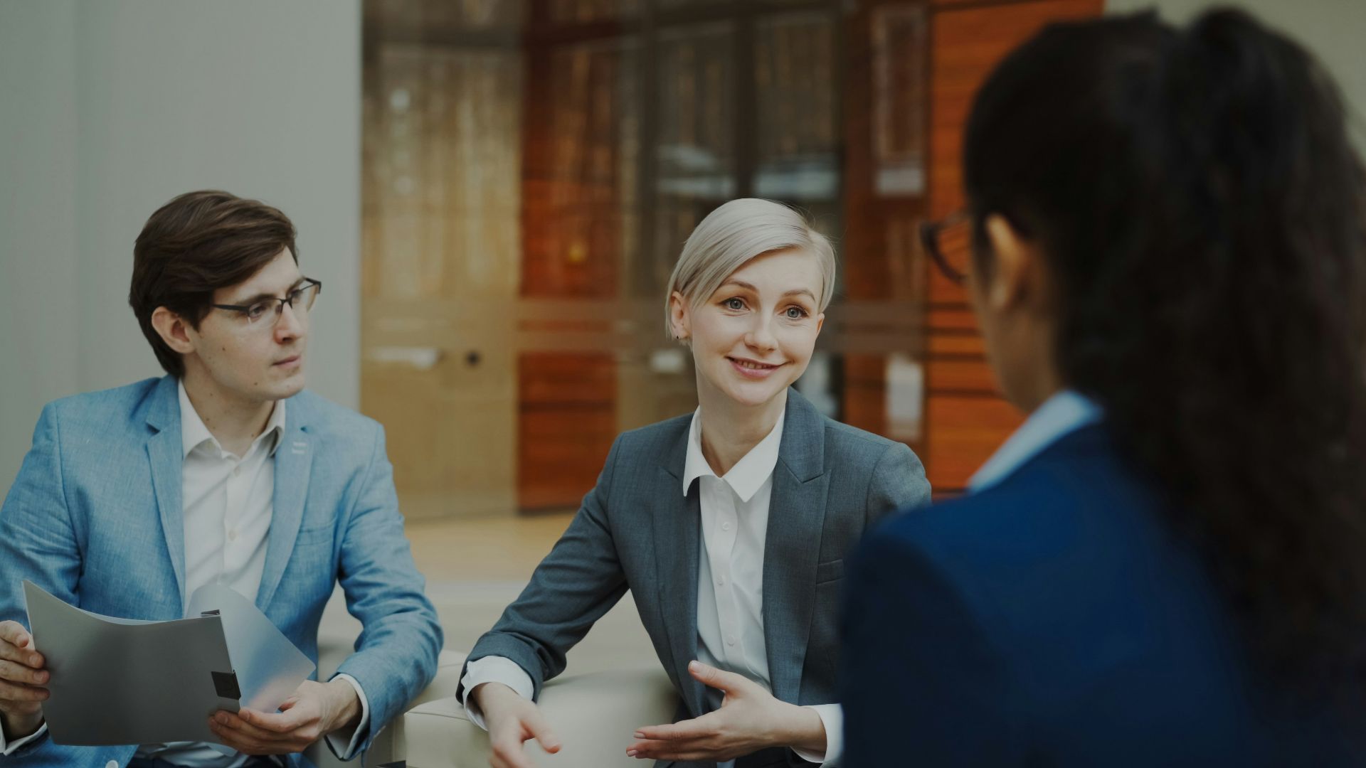 Three people in a business meeting discussing documents