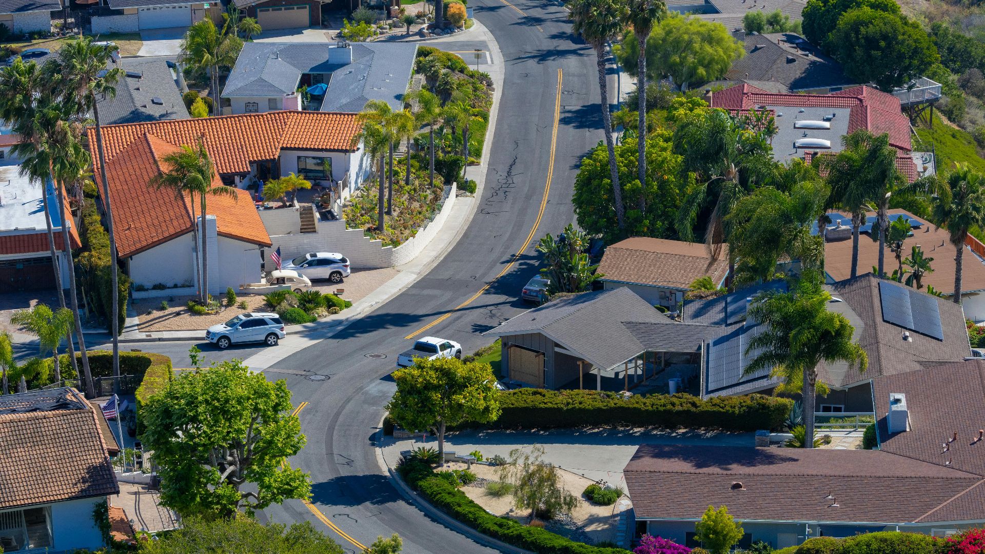 Aerial view of a charming San Clemente suburb with palm trees and red roofs on a sunny day.
