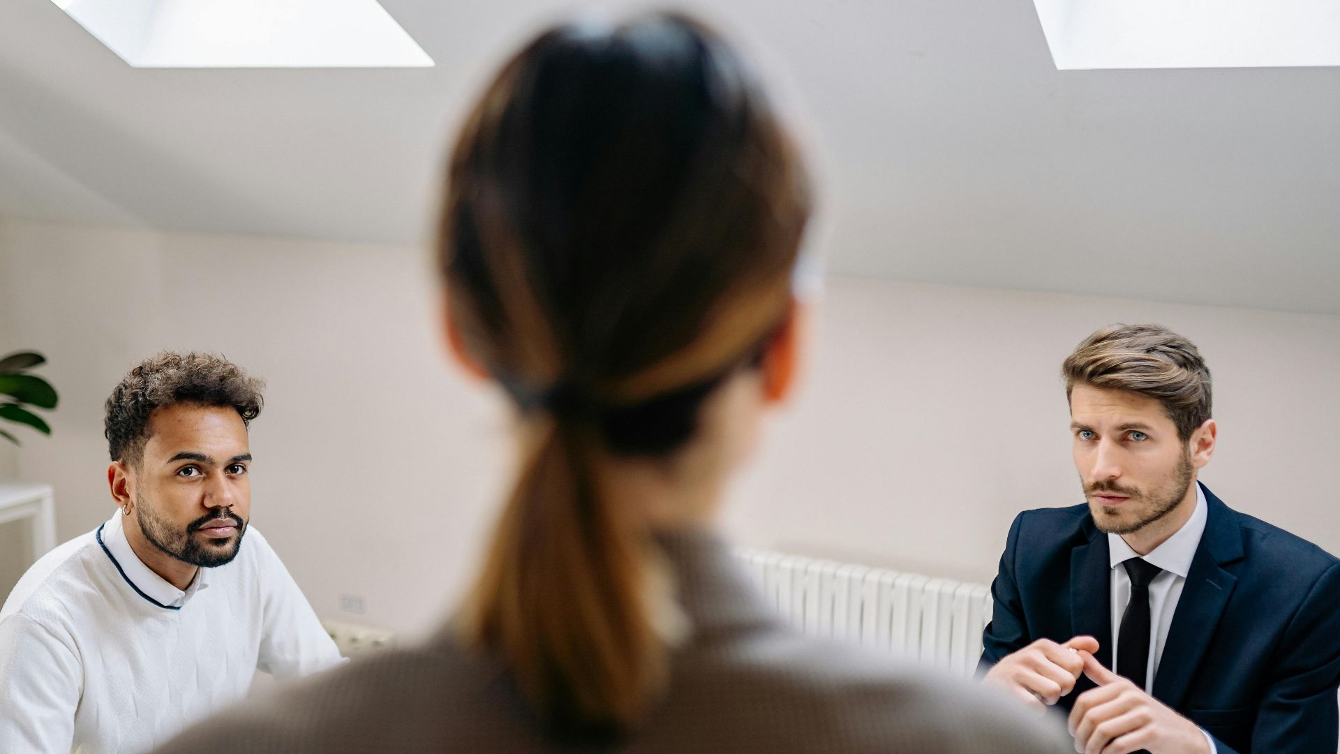 A professional business meeting involving three adults in a modern office setting.