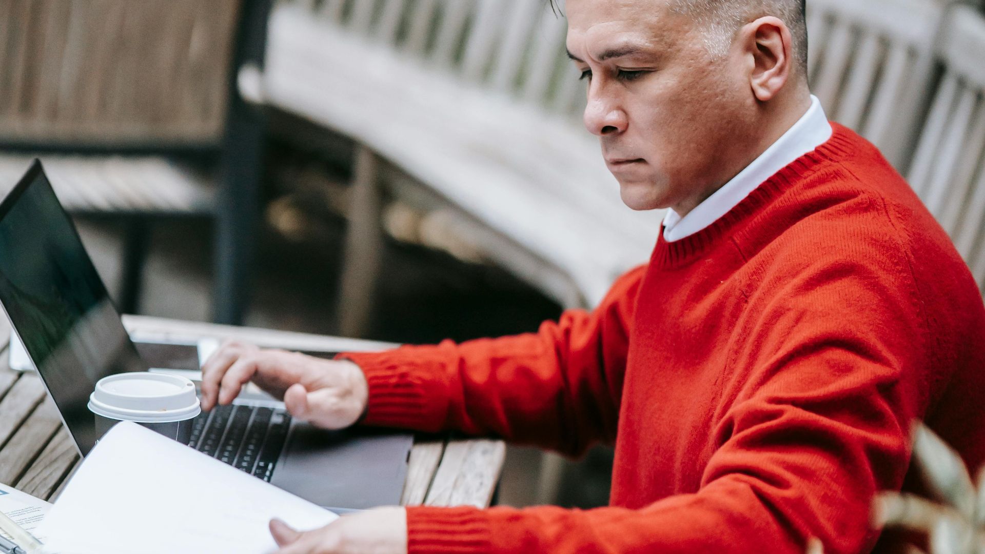 Businessman focused on remote work using a laptop in an outdoor setting.