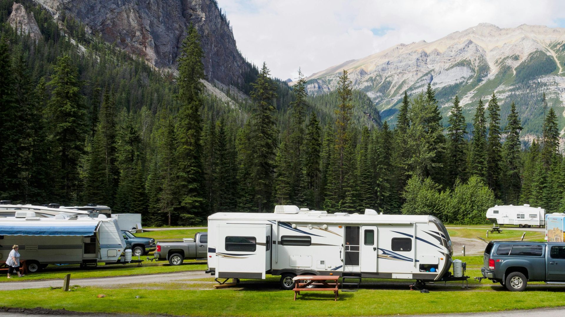 A beautiful campsite featuring RVs amidst lush forests and towering mountains for a peaceful getaway.