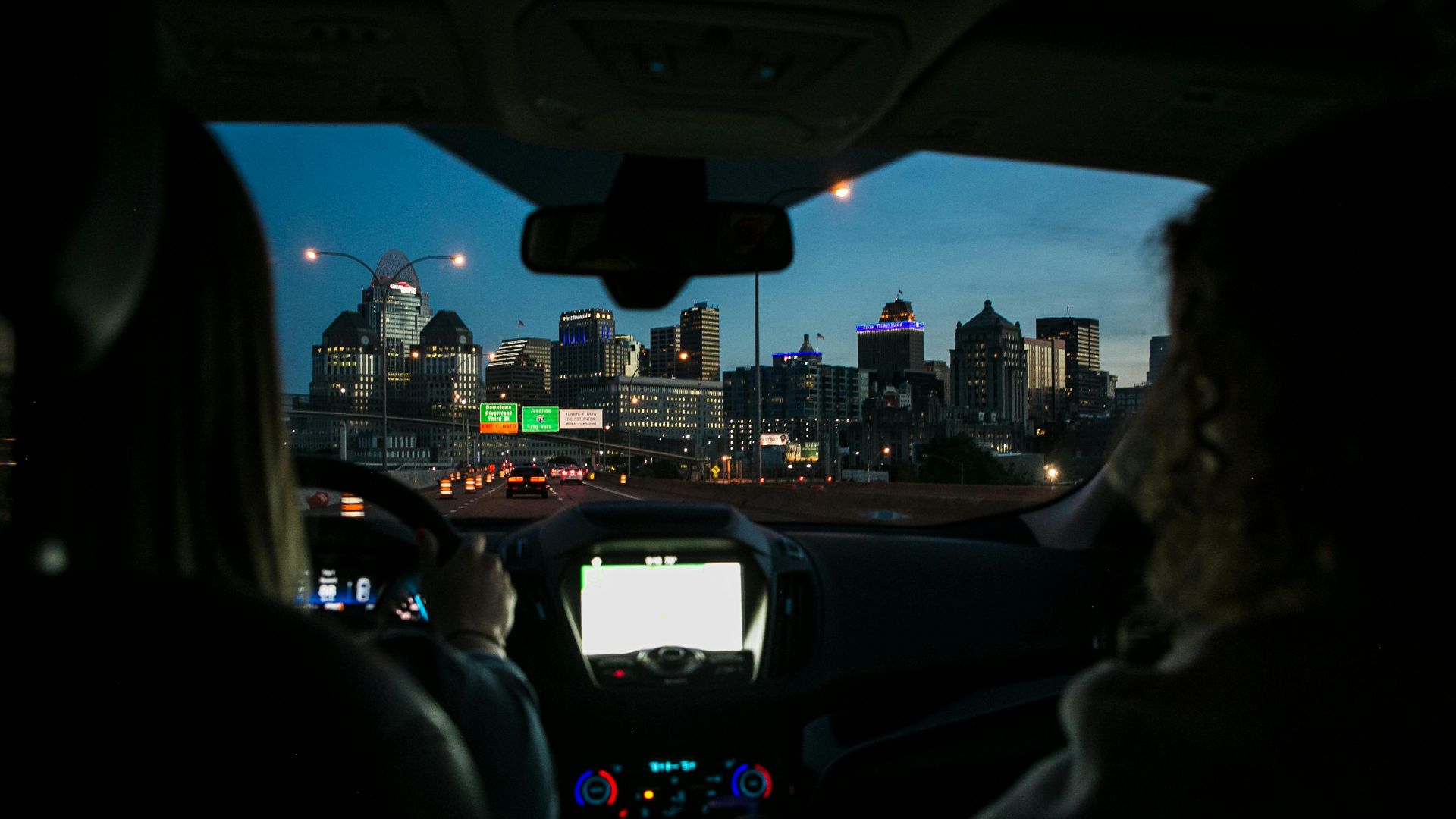 View of city skyline during night drive, captured through car windshield.
