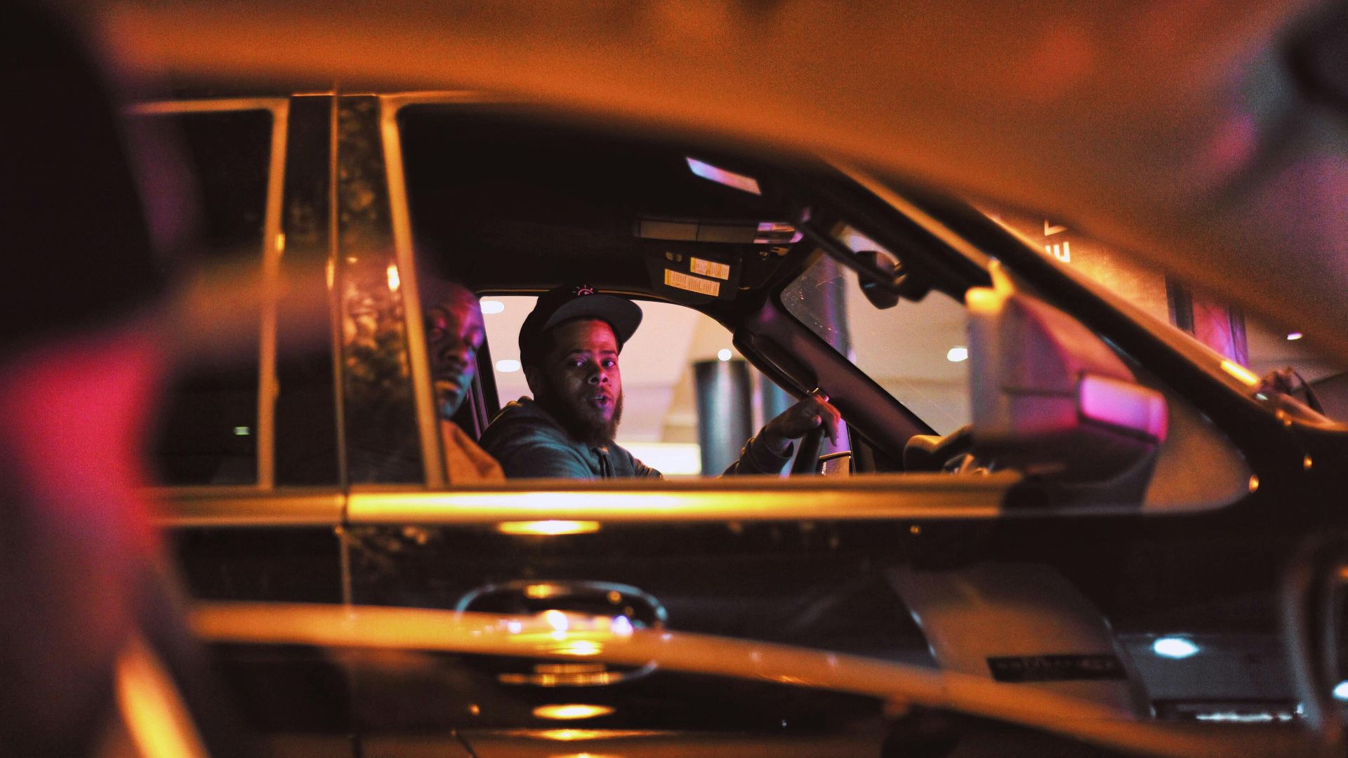 A man driving in the city at night, captured with vibrant lights and urban atmosphere.