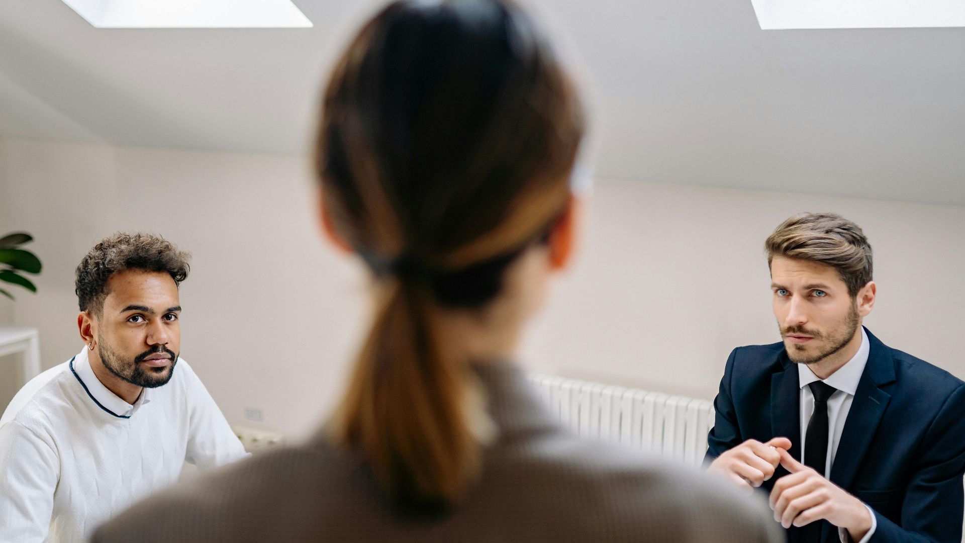 A professional business meeting involving three adults in a modern office setting.
