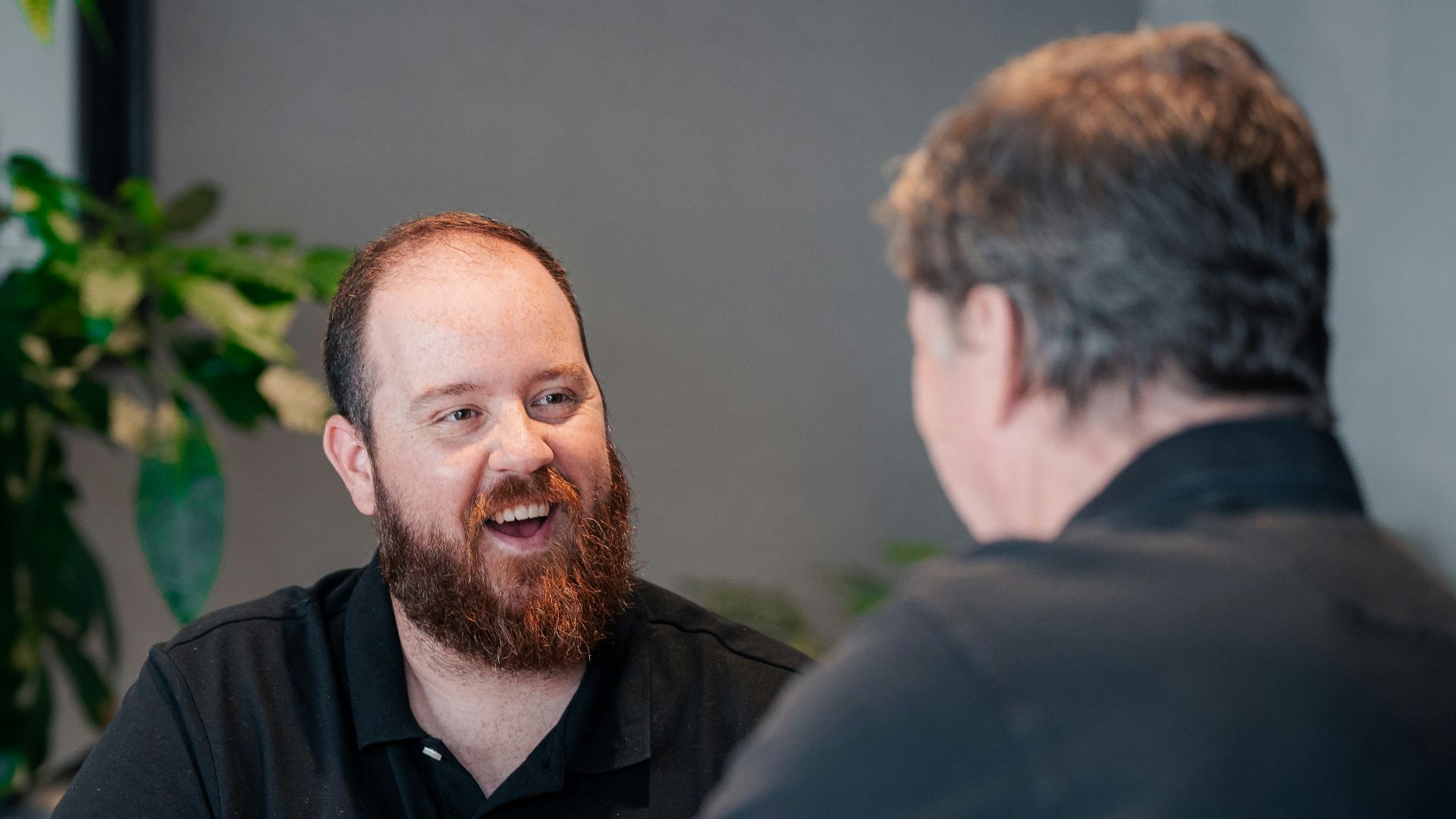 two men sitting at a table talking to each other