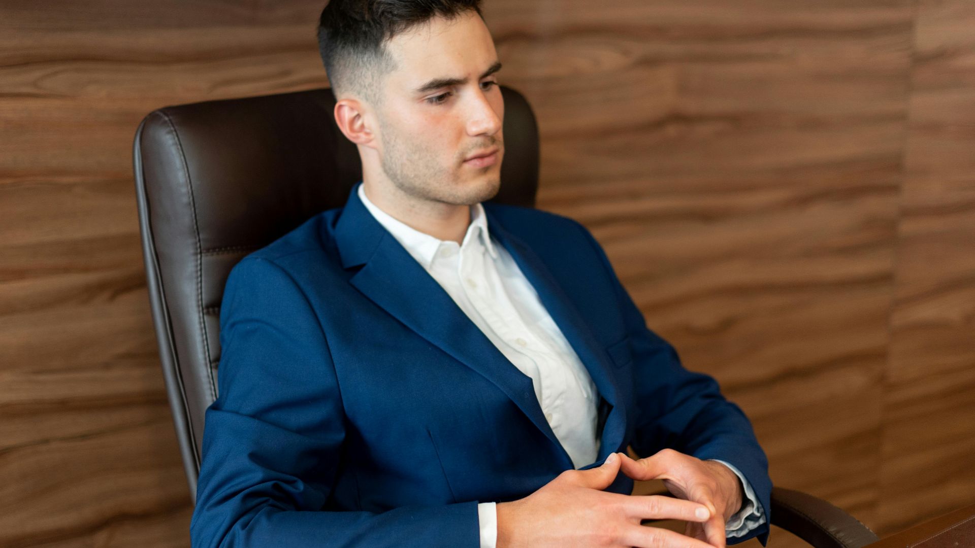 Professional man in a blue suit seated in an office, reflecting a focused business environment.