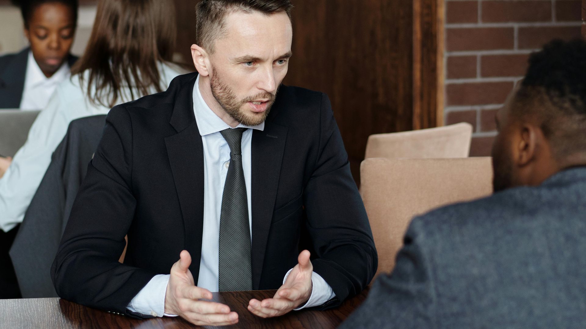 Professionals in suits having a focused business discussion in a stylish café.