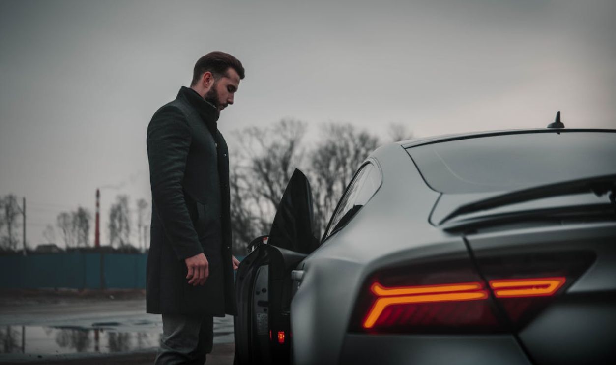Man in Black Coat Standing Beside Black Car
