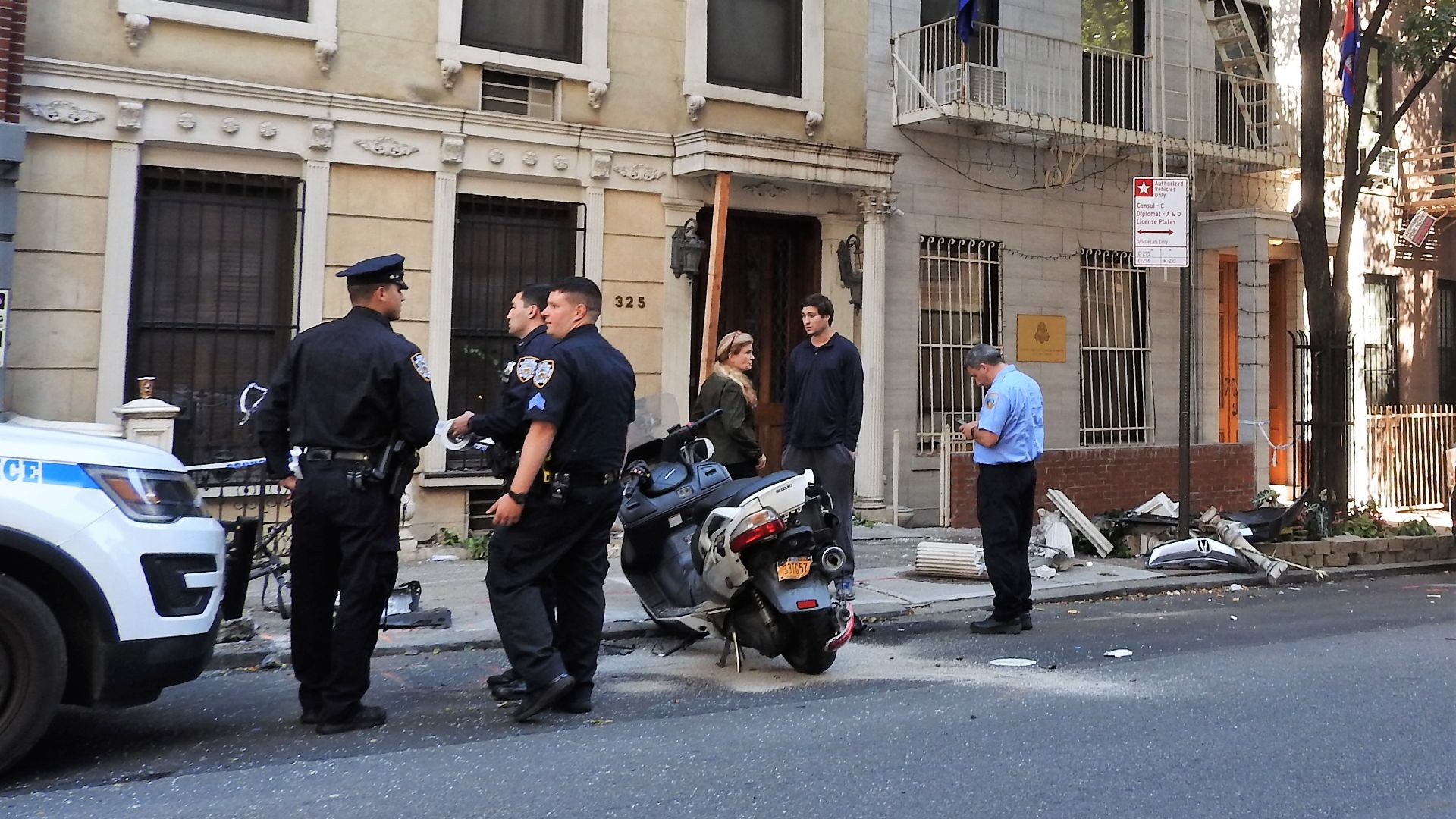 Police study the site where a car went astray into an apartment house stoop.
