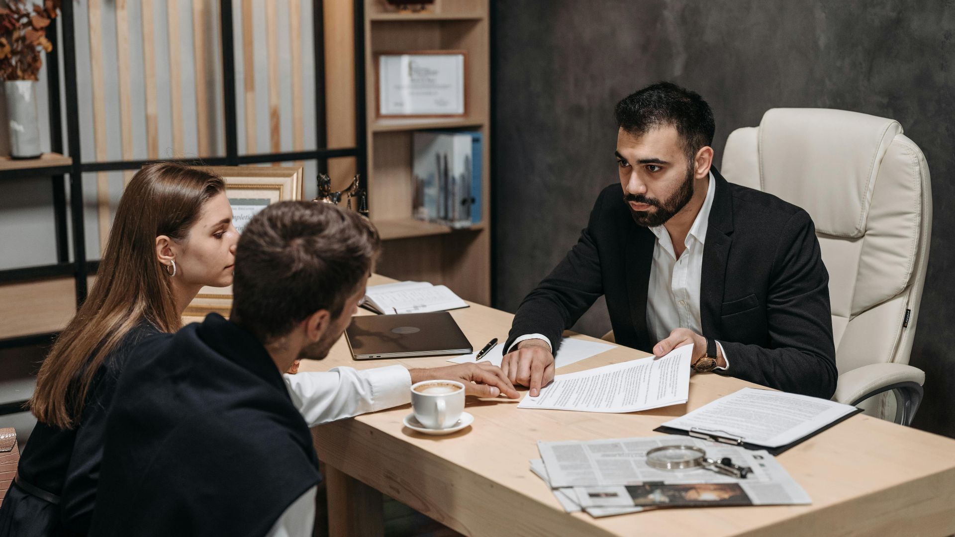 Lawyer discussing legal documents with clients at office desk.