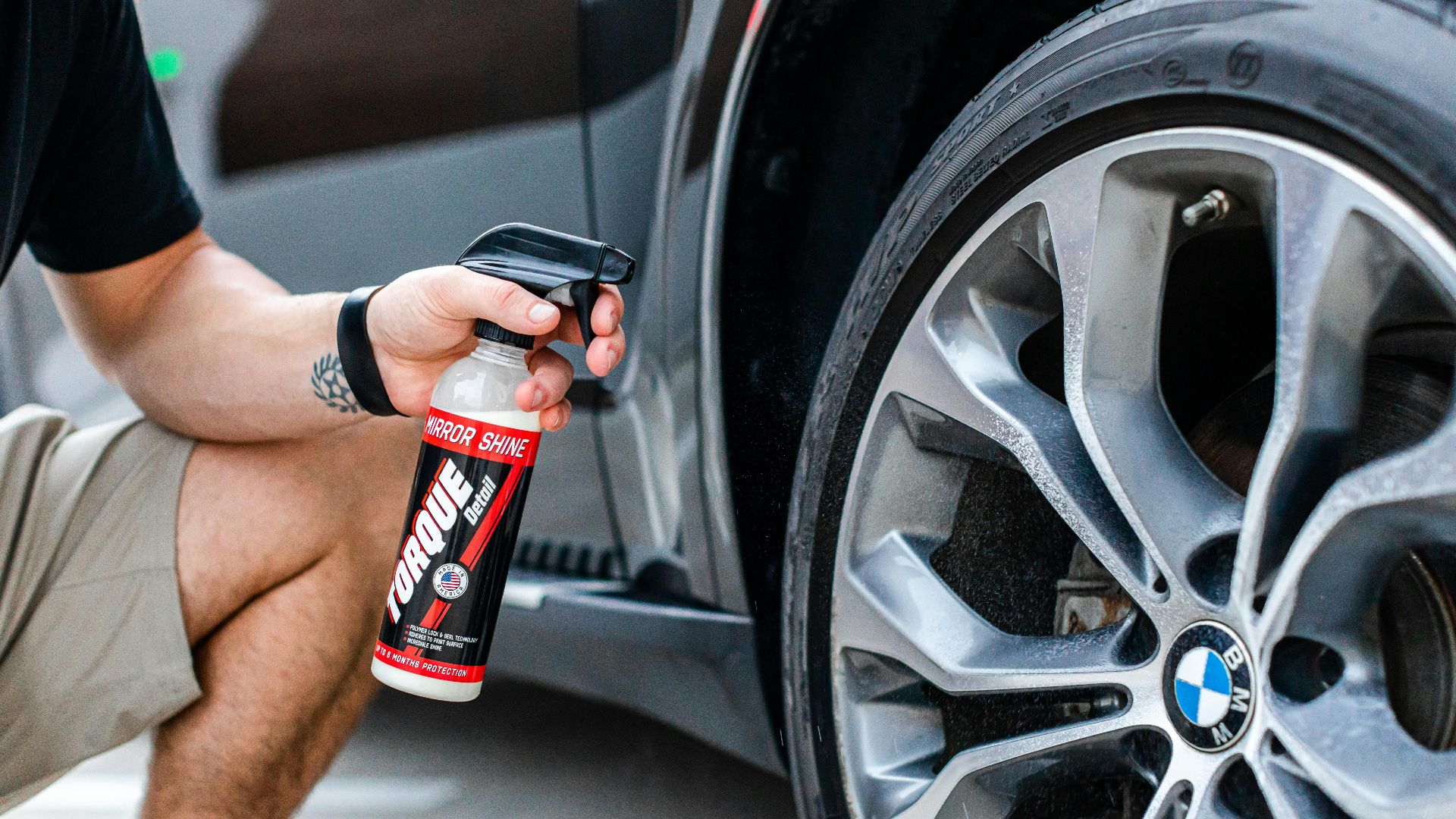 A person is applying tire shine on a BMW wheel, showcasing a luxury car's shiny finish.