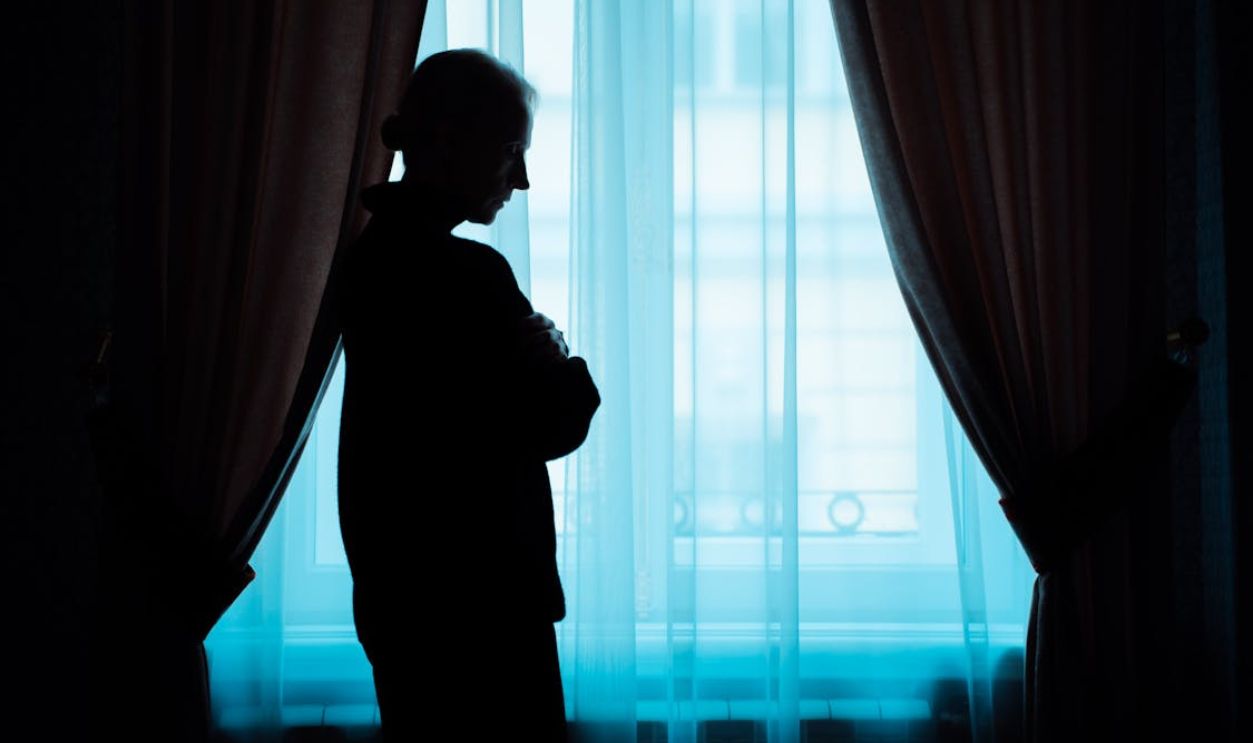 Silhouette of a Person Standing Near a Window