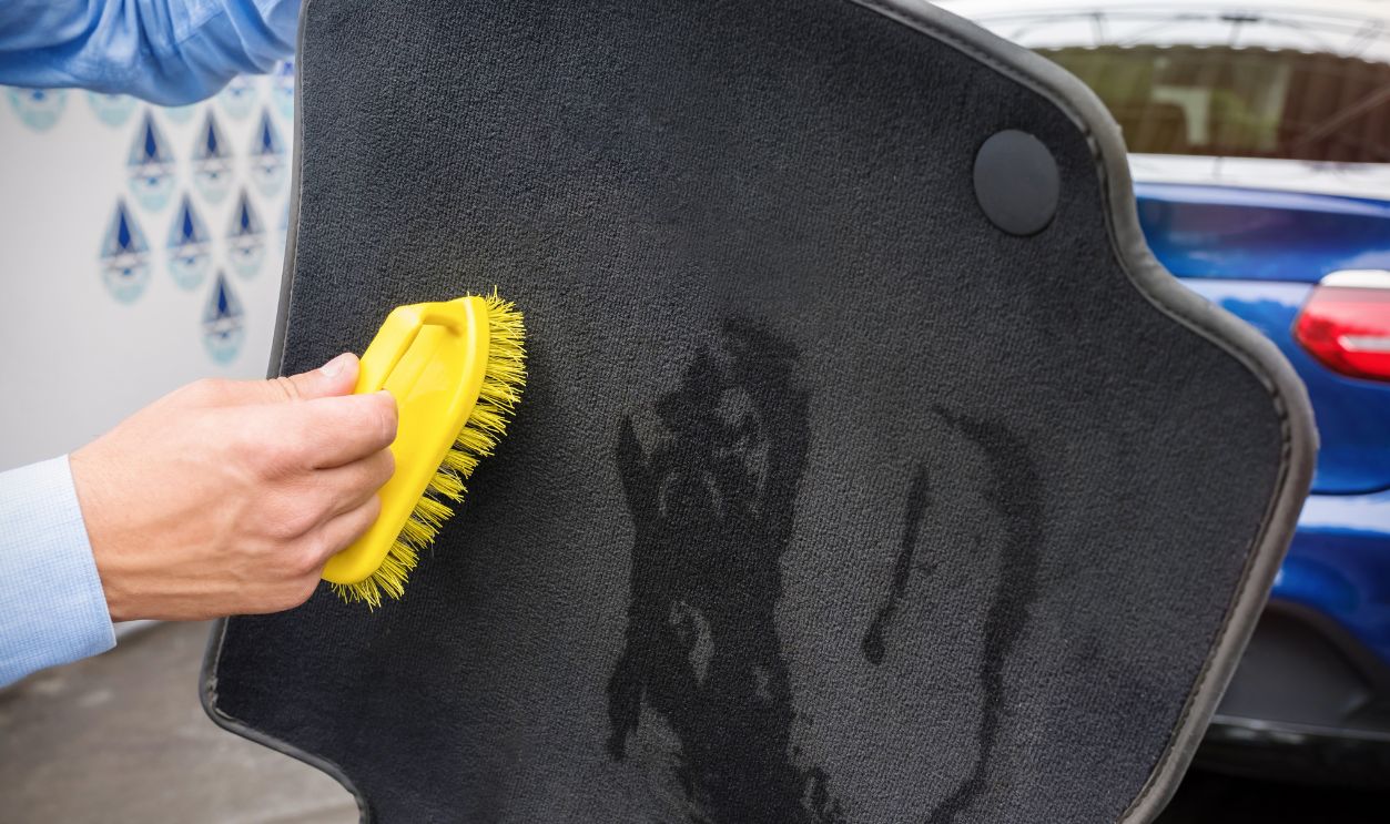 The hand of the person cleans an automobile rug
