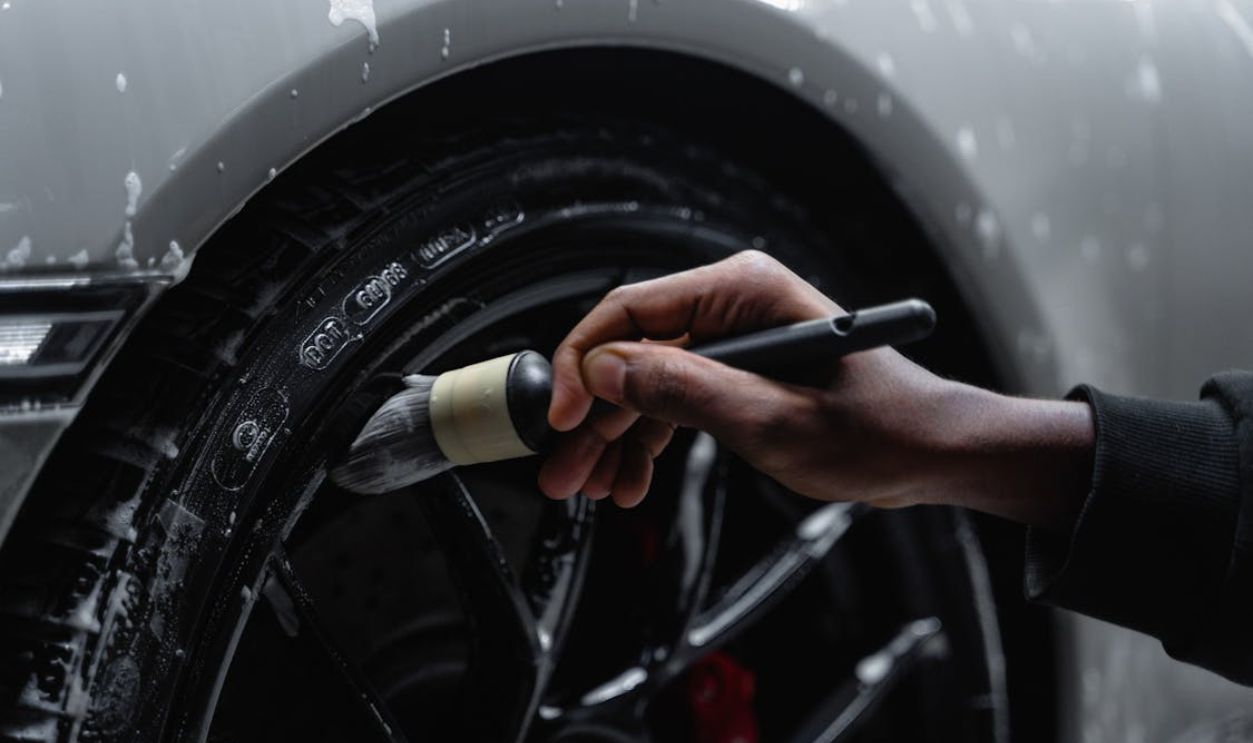A Close-Up Shot of a Person Brushing the Wheel of a Car