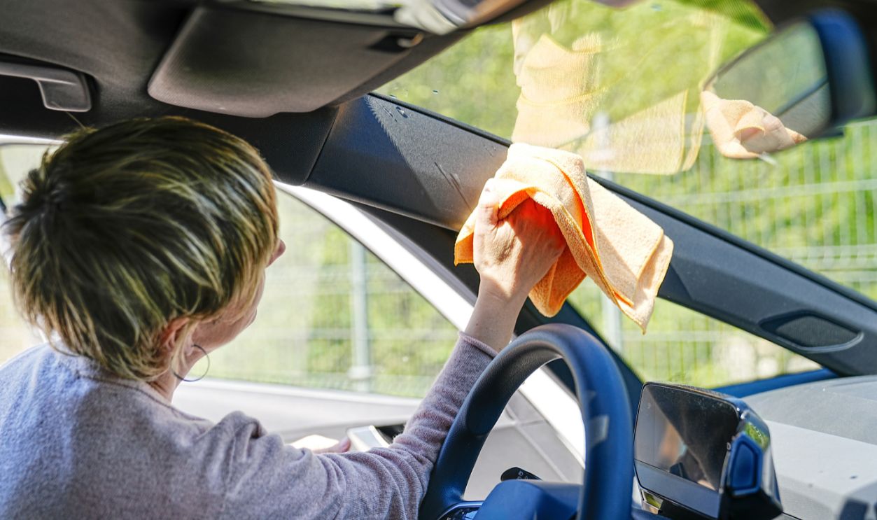 2455922291 Inside view of a woman carefully cleaning the windshield on a sunny day