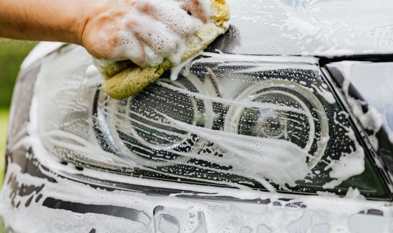 A Person Washing a the Headlight of a Car