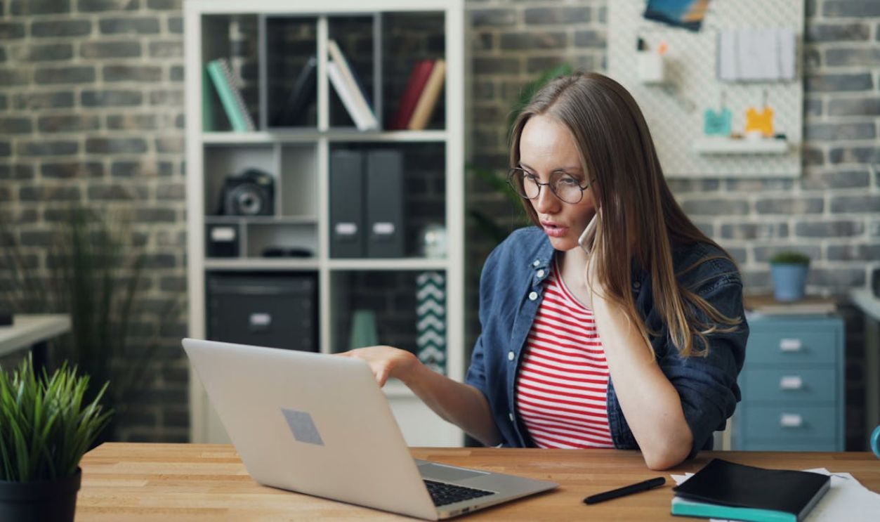 Woman Talking on Phone and Looking at Laptop